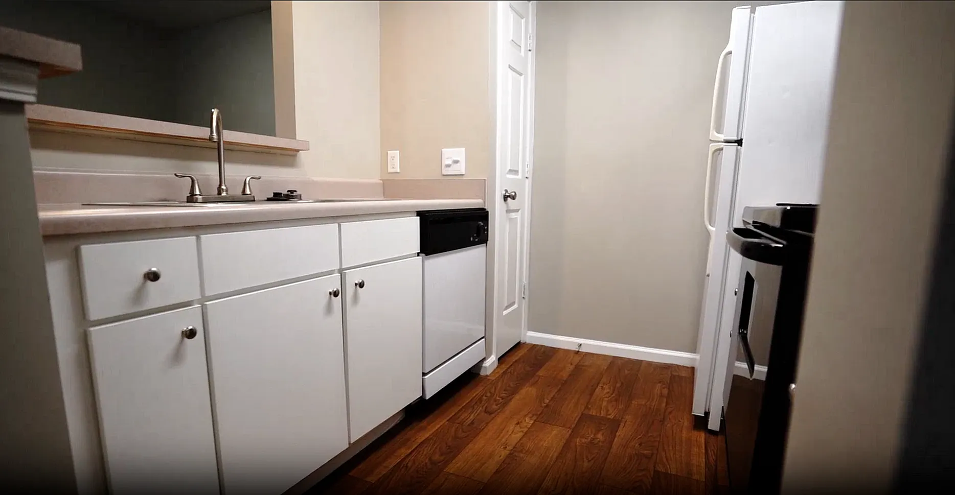 Charming kitchen with modern white cabinetry, sleek countertops, and warm wood flooring, perfect for culinary creativity.