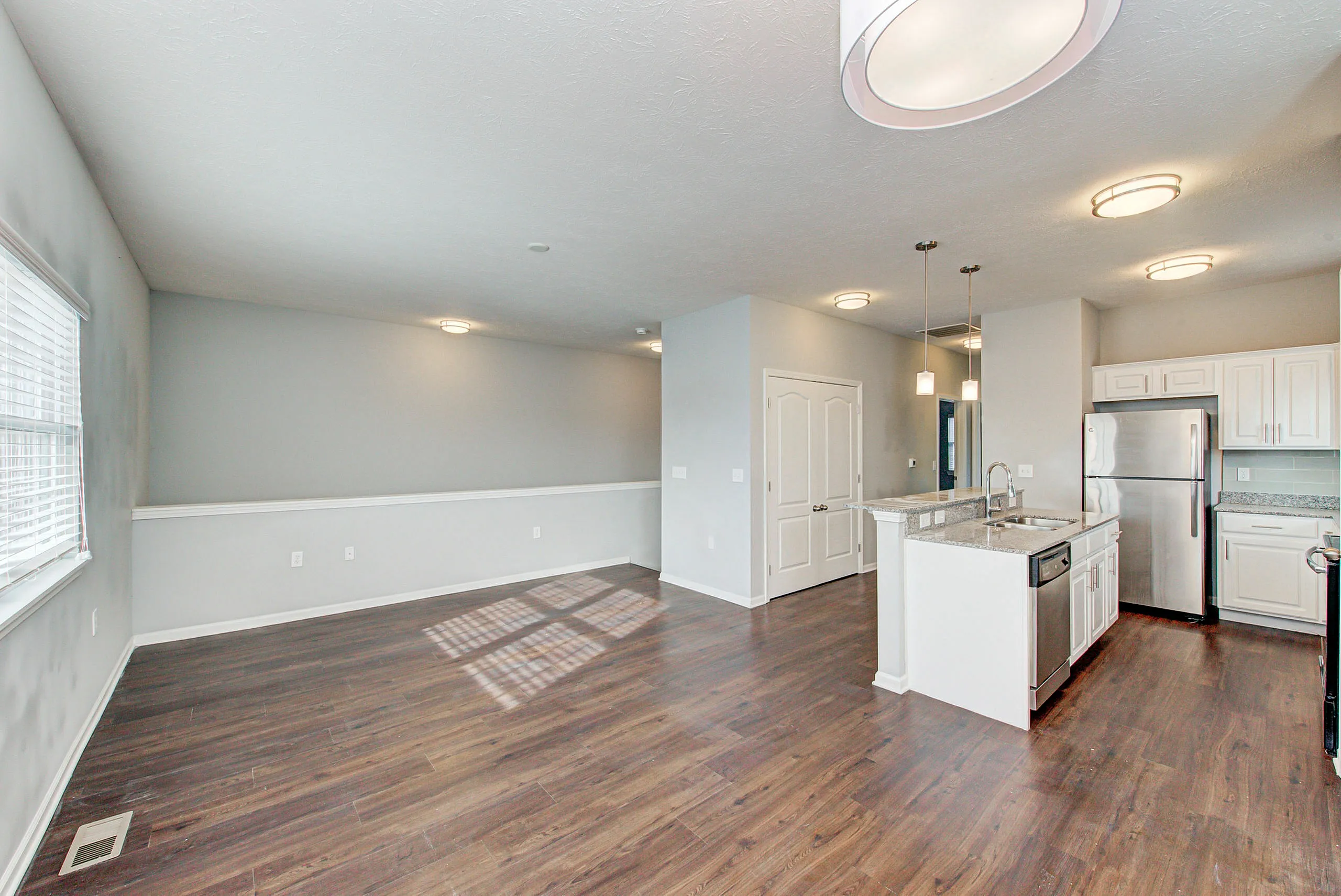 Modern open-concept kitchen and living space with elegant hardwood floors, stainless steel appliances, and abundant natural light.