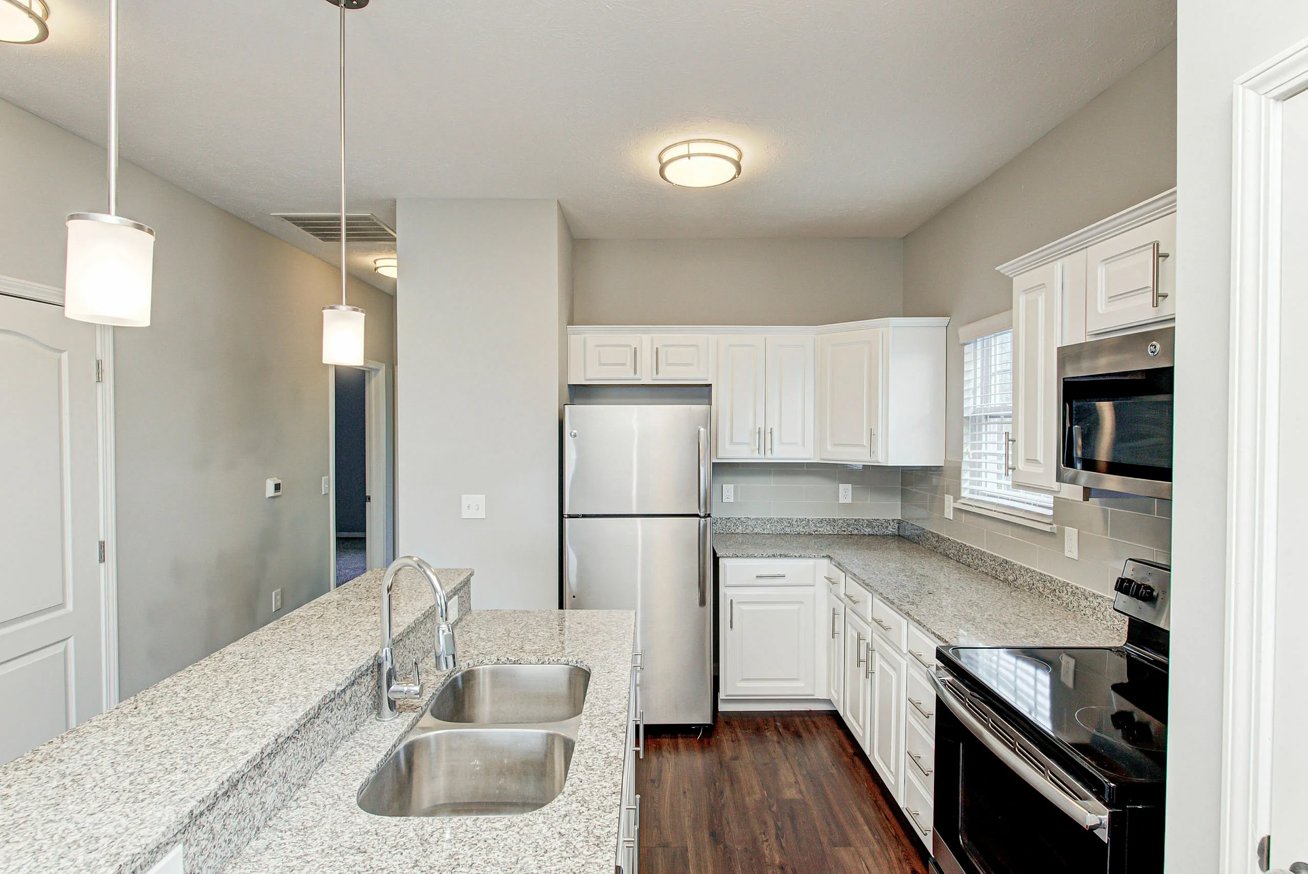 Modern kitchen with sleek granite countertops, stainless steel appliances, and elegant pendant lighting.