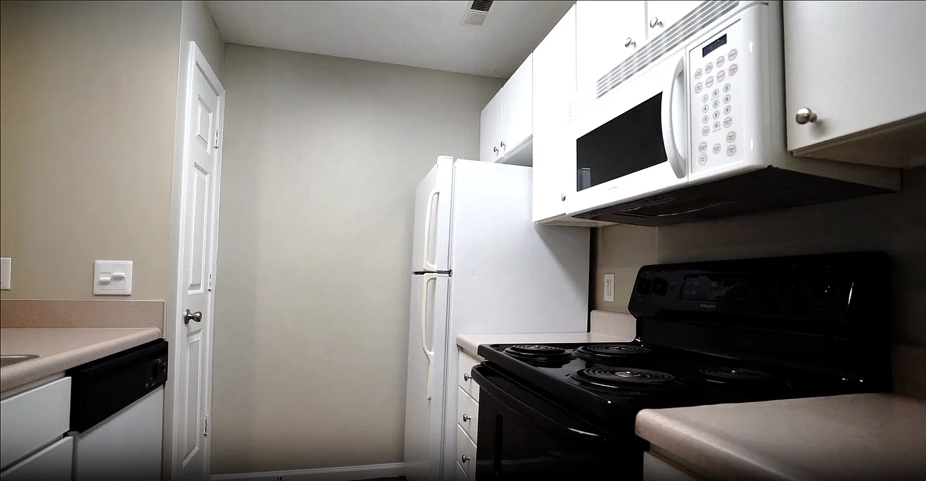 Modern kitchen with sleek white cabinetry, built-in microwave, and spacious countertops.