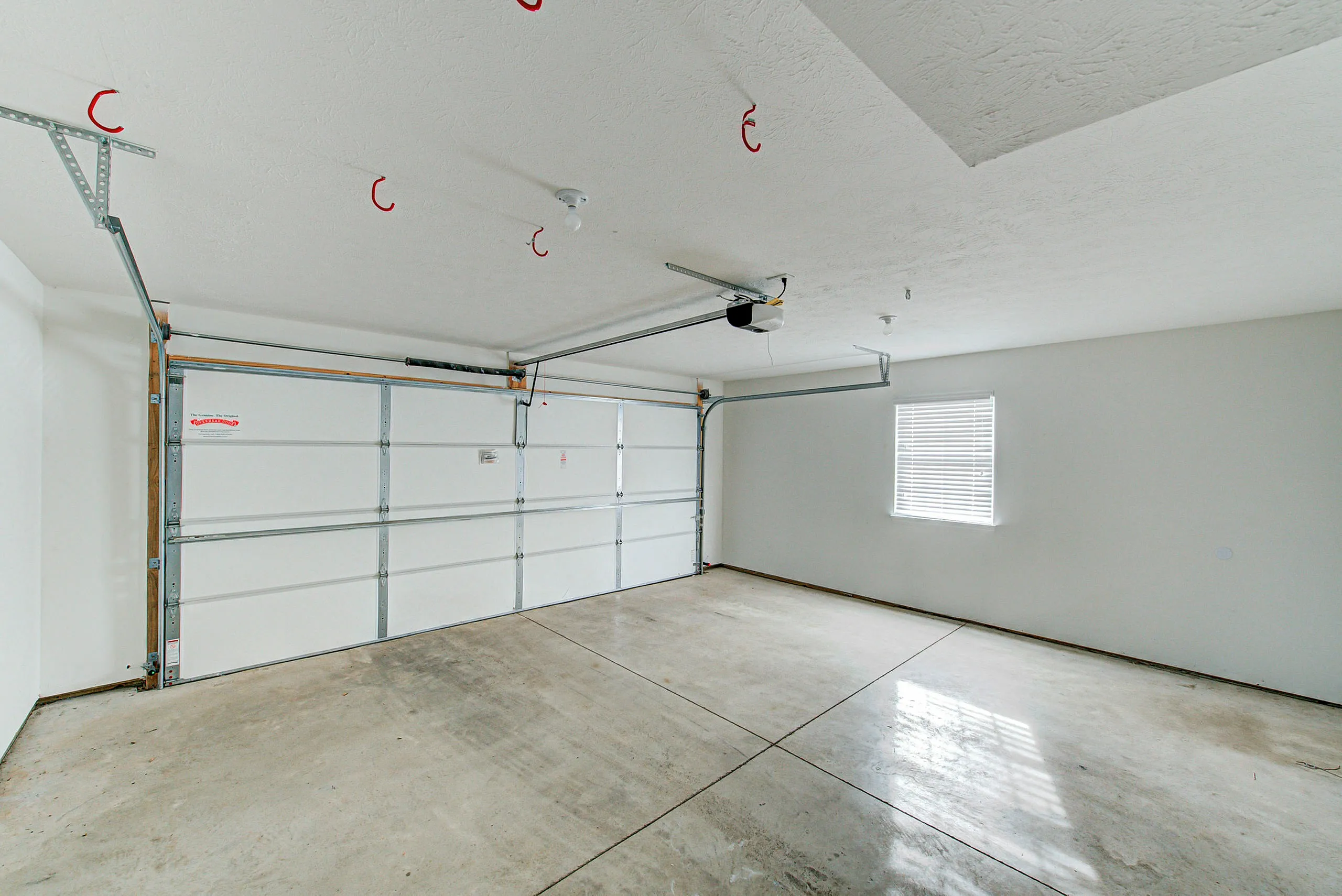 Spacious modern garage with epoxy flooring and ample natural light, ready to accommodate vehicles or storage needs.