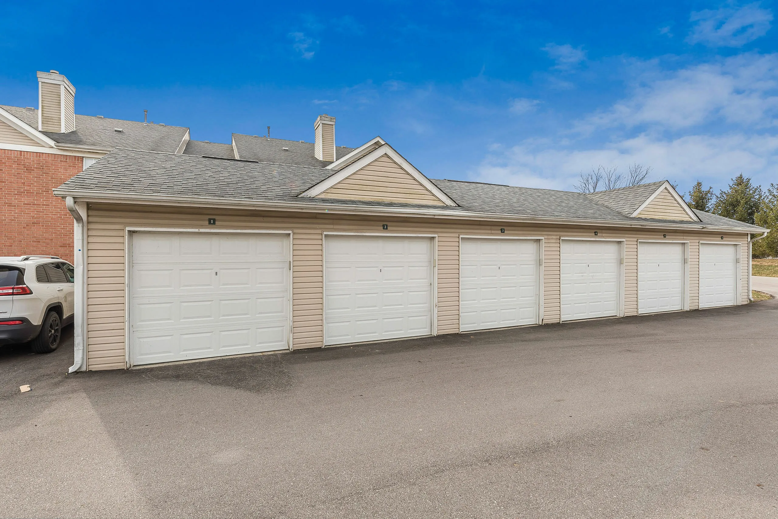 Row of well-maintained garages providing ample parking space with a sleek design, set against a bright blue sky.