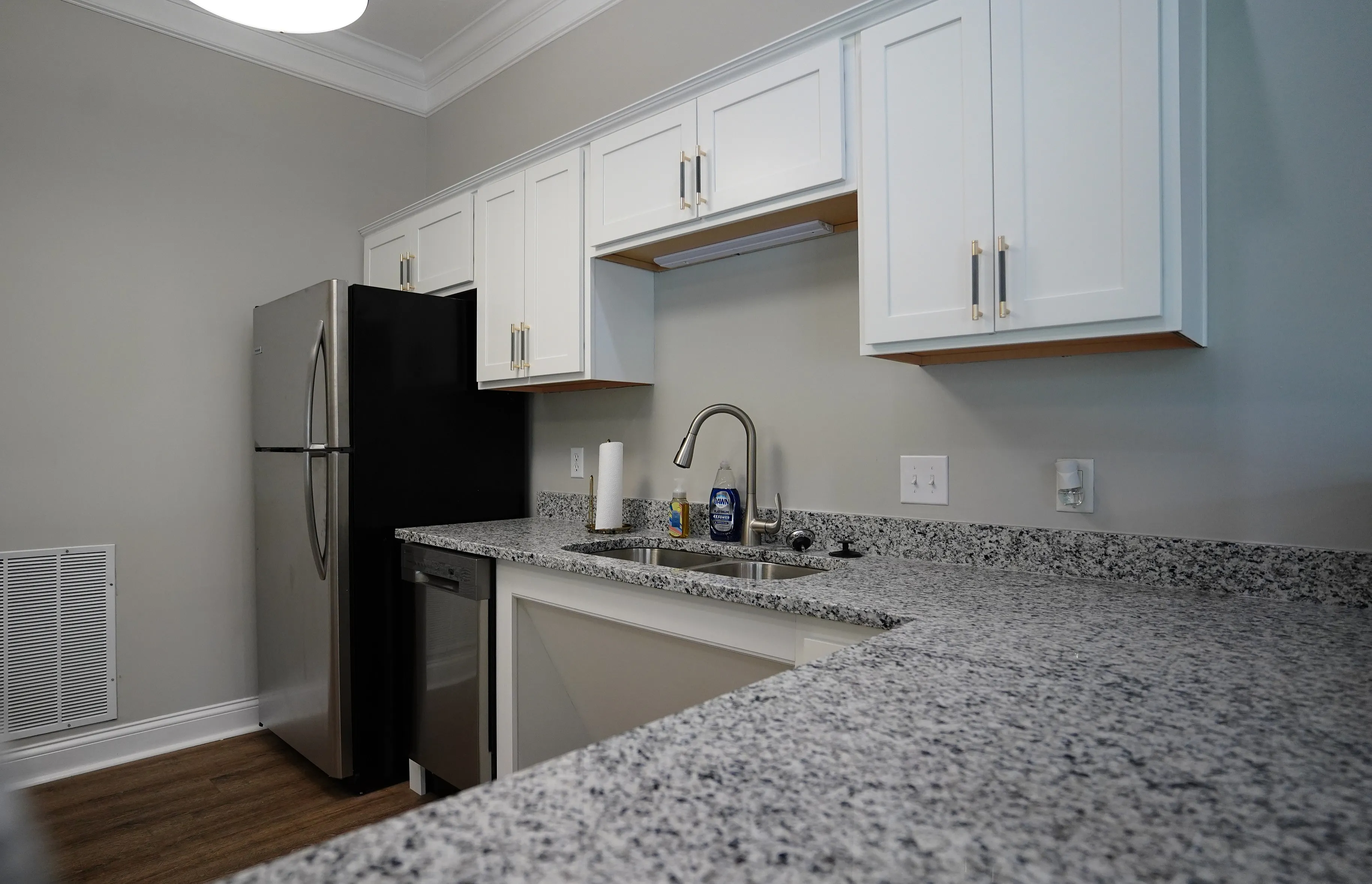 Modern kitchen with sleek stainless steel appliances, elegant white cabinets, and granite countertops, perfect for culinary creativity.