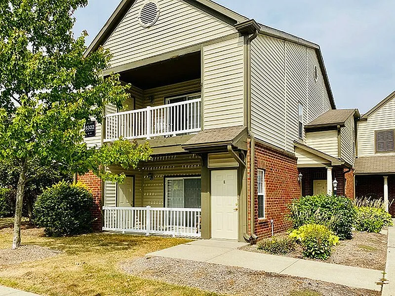 Charming two-story apartment exterior featuring welcoming balconies and lush landscaping.
