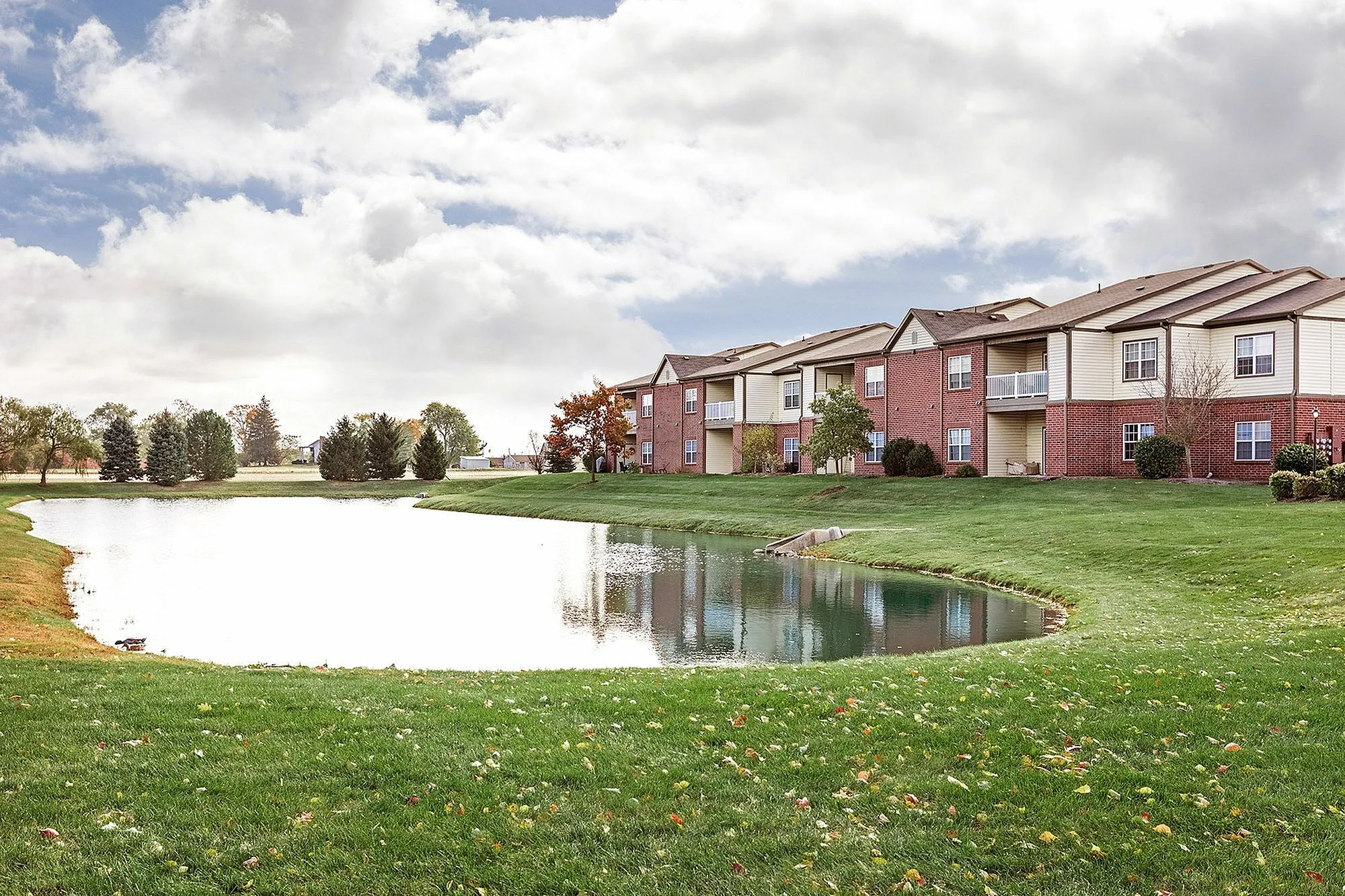 Charming apartment complex with picturesque lakeside views, surrounded by lush greenery and vibrant autumn foliage.