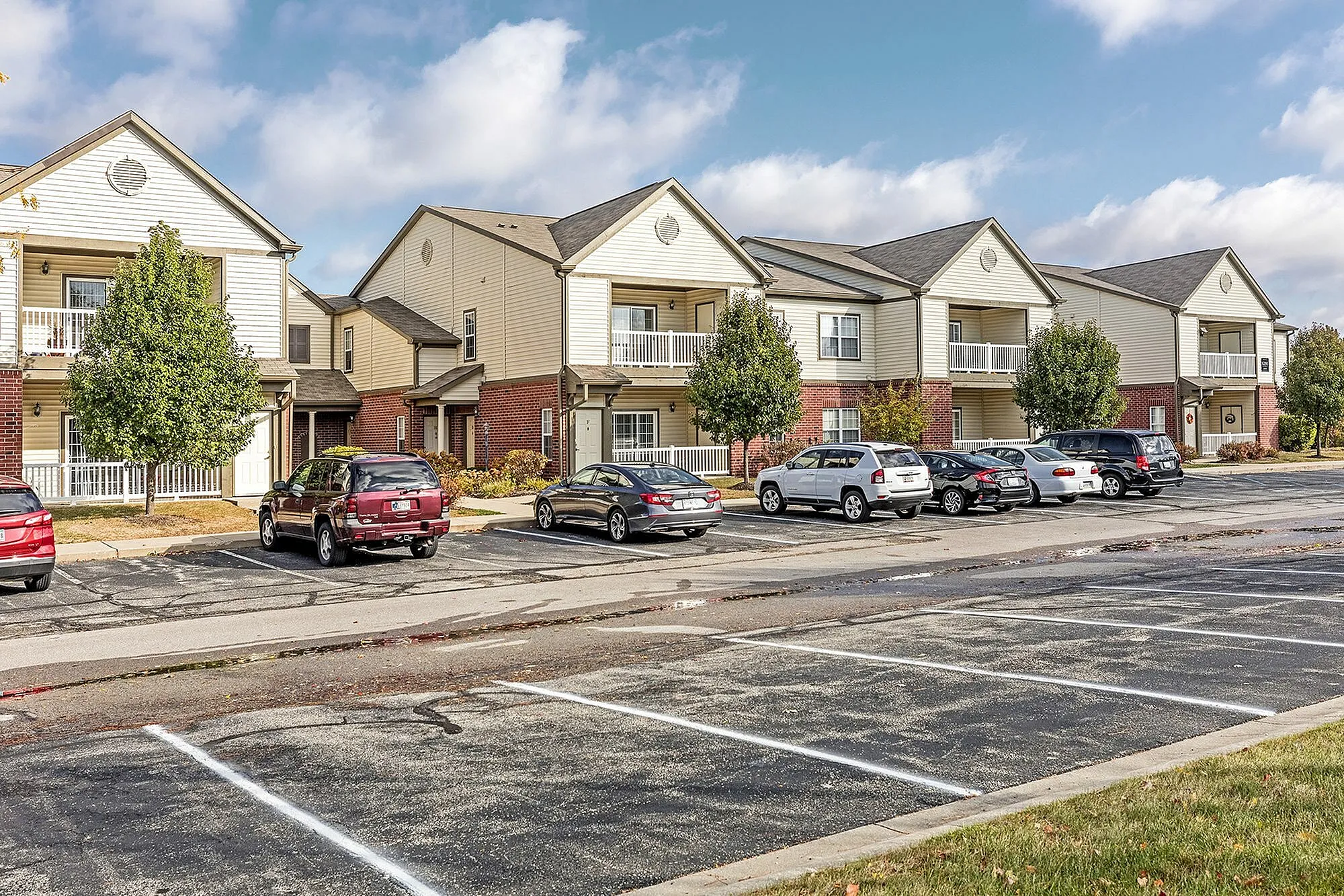 Charming suburban apartment complex with modern two-story buildings, ample parking, and scenic landscaping.