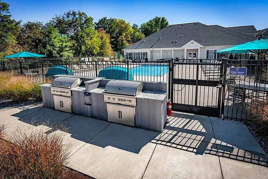 Inviting outdoor space featuring a modern grill area, sparkling swimming pool, and poolside seating with vibrant umbrellas for relaxation.