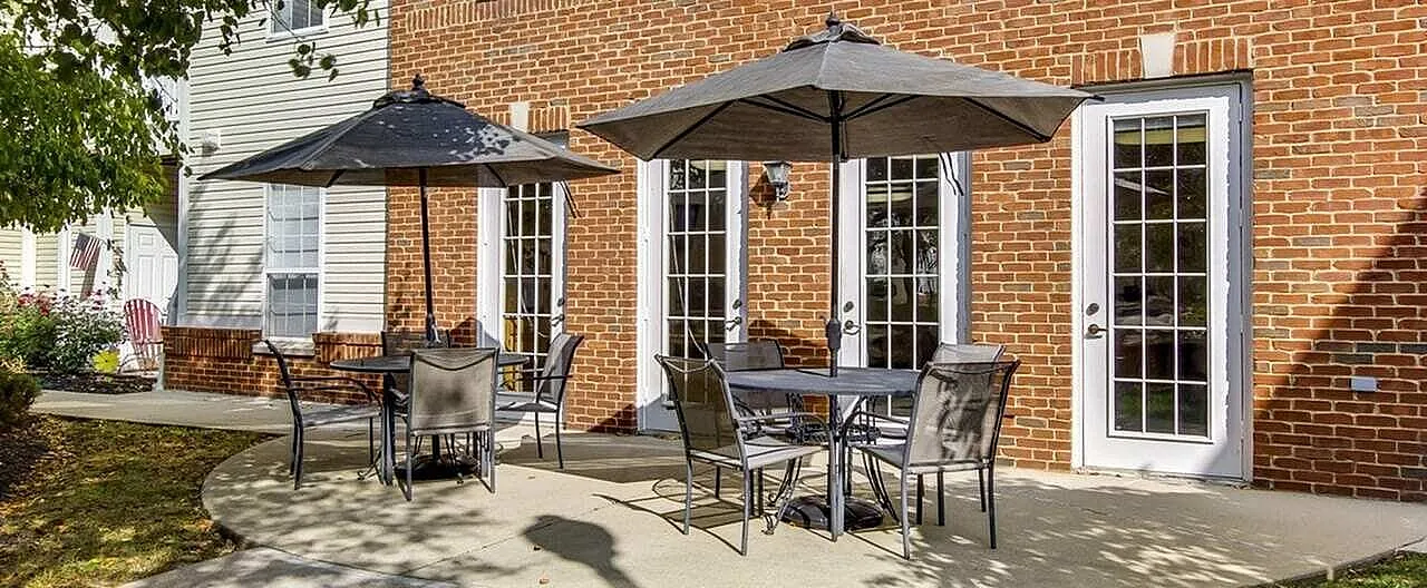 Charming patio area with cozy seating, large umbrellas, and brick facade, perfect for outdoor relaxation.
