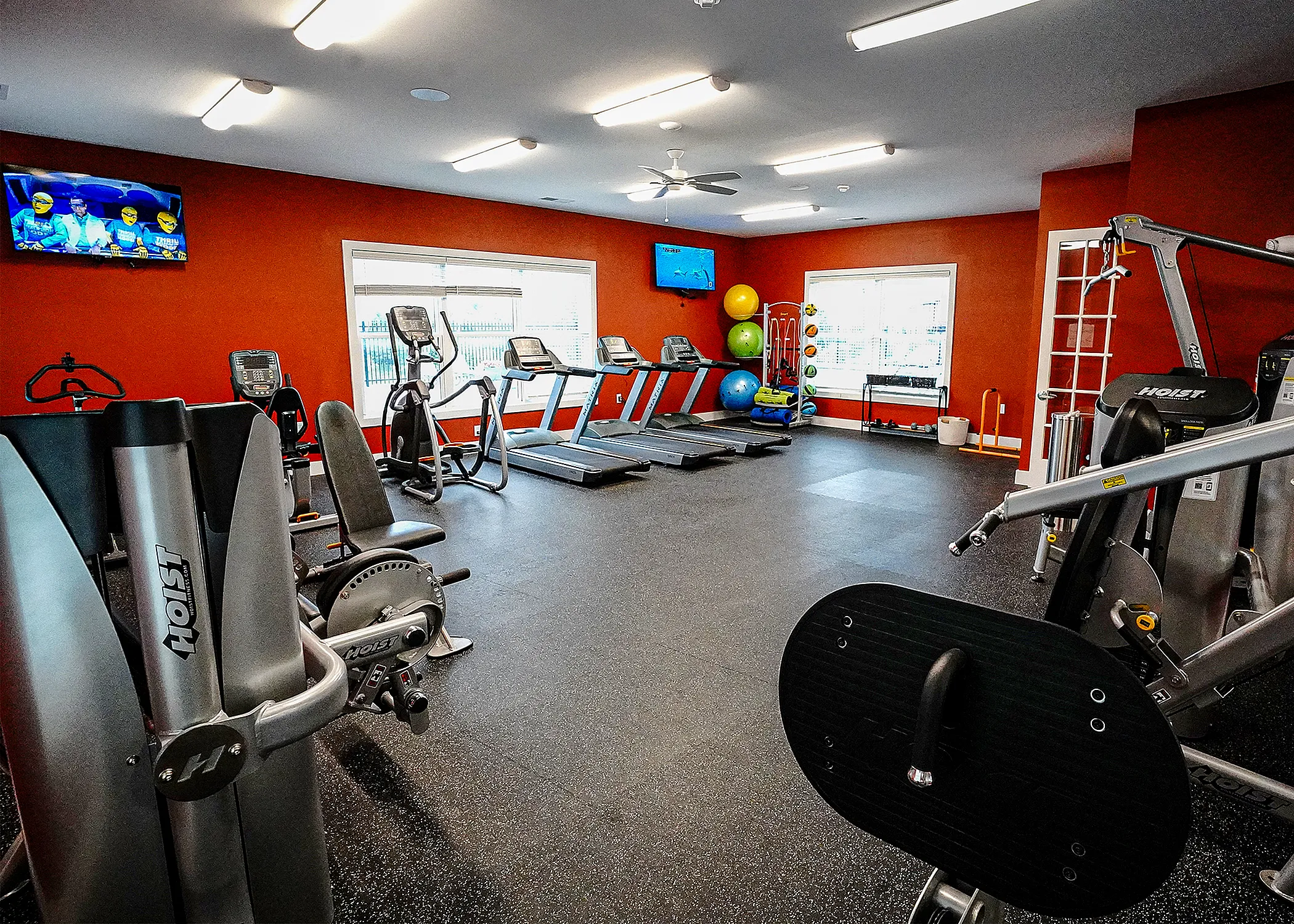Modern fitness center with state-of-the-art equipment including treadmills, exercise bikes, and a vibrant atmosphere with natural light.