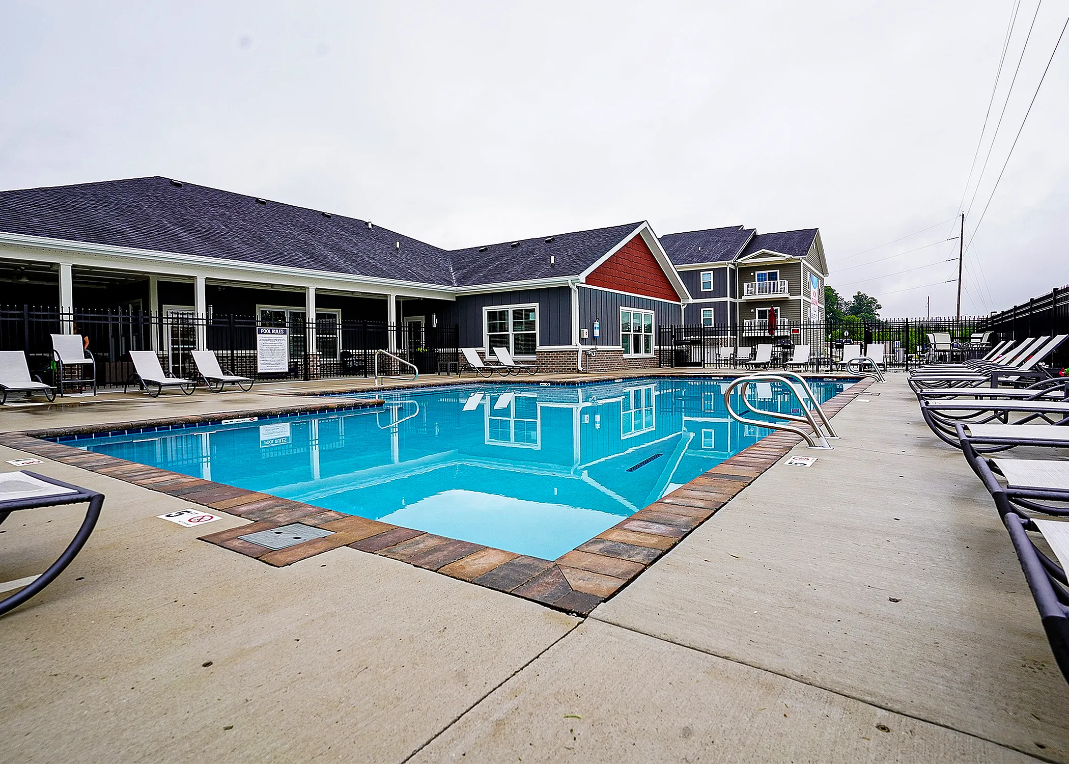 Inviting apartment complex with a modern outdoor pool area, surrounded by comfortable lounge chairs and lush greenery.
