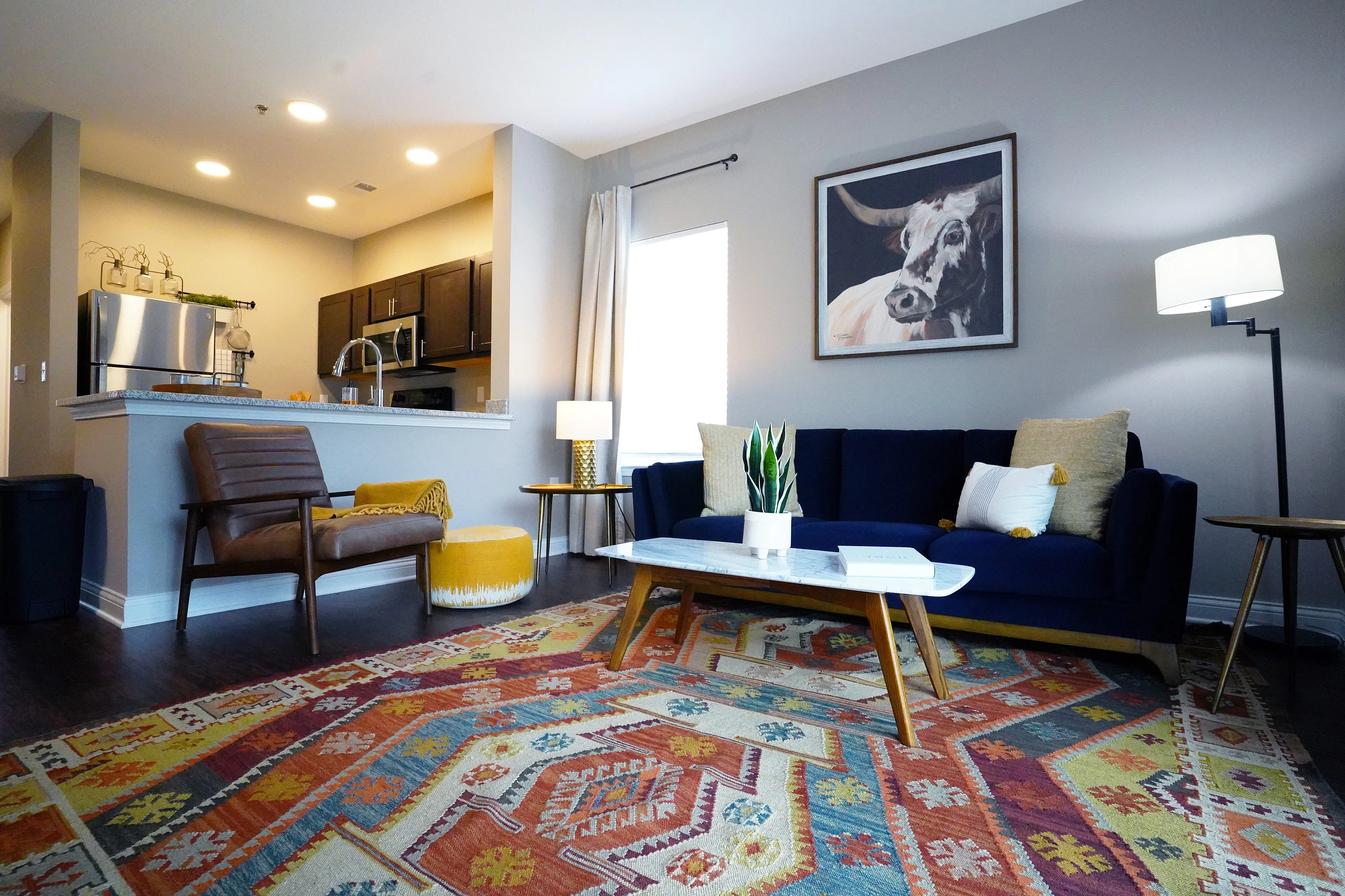 Chic living area with modern kitchen, cozy seating, vibrant rug, and stylish artwork creating a welcoming ambiance.