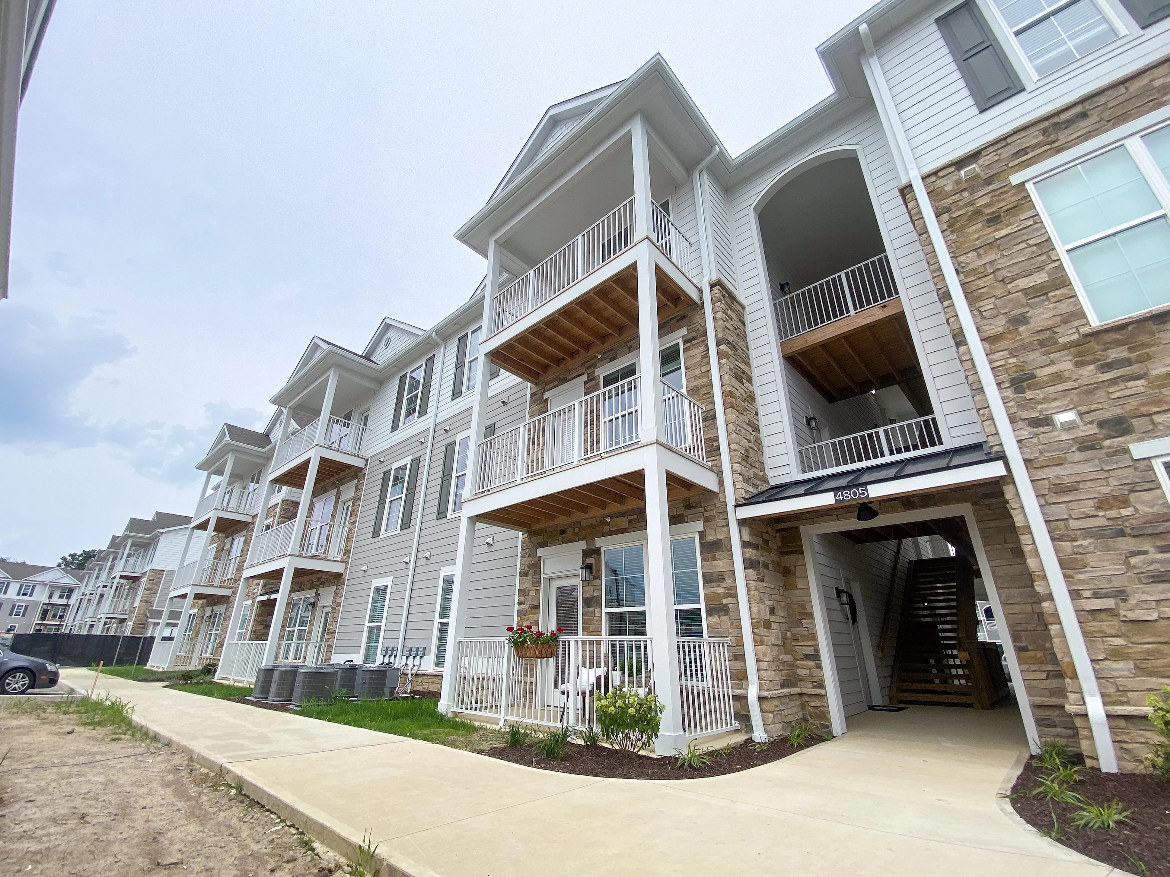 Modern apartment complex with elegant balconies and stone accents, offering a contemporary living experience in a suburban setting.