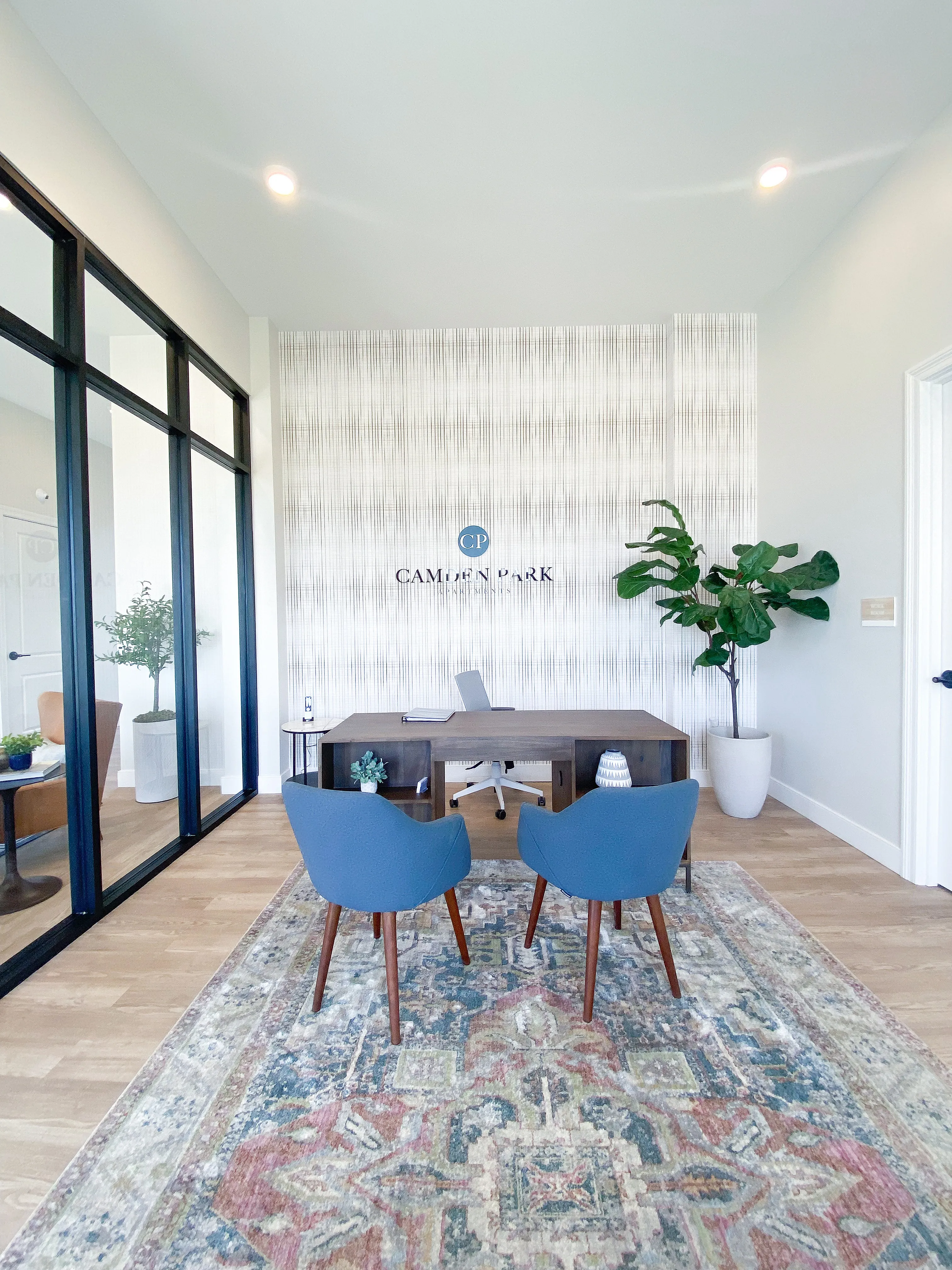Elegant office space with modern decor, featuring stylish blue chairs, a sleek wooden desk, and vibrant plants, creating a refreshing and professional ambiance.