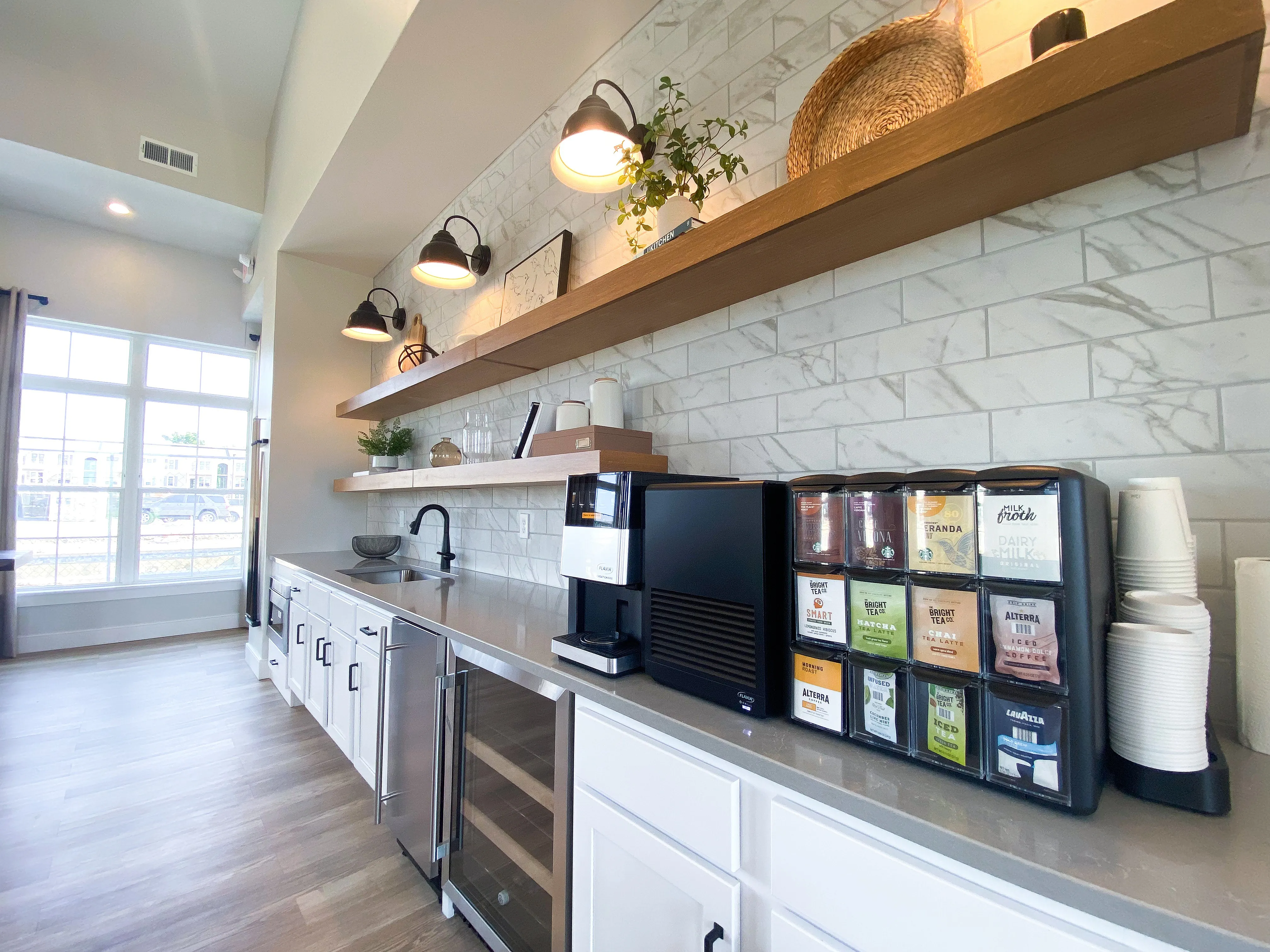 Modern kitchen area with sleek countertops, sophisticated shelving, and a built-in beverage station under warm lighting for an inviting ambiance.