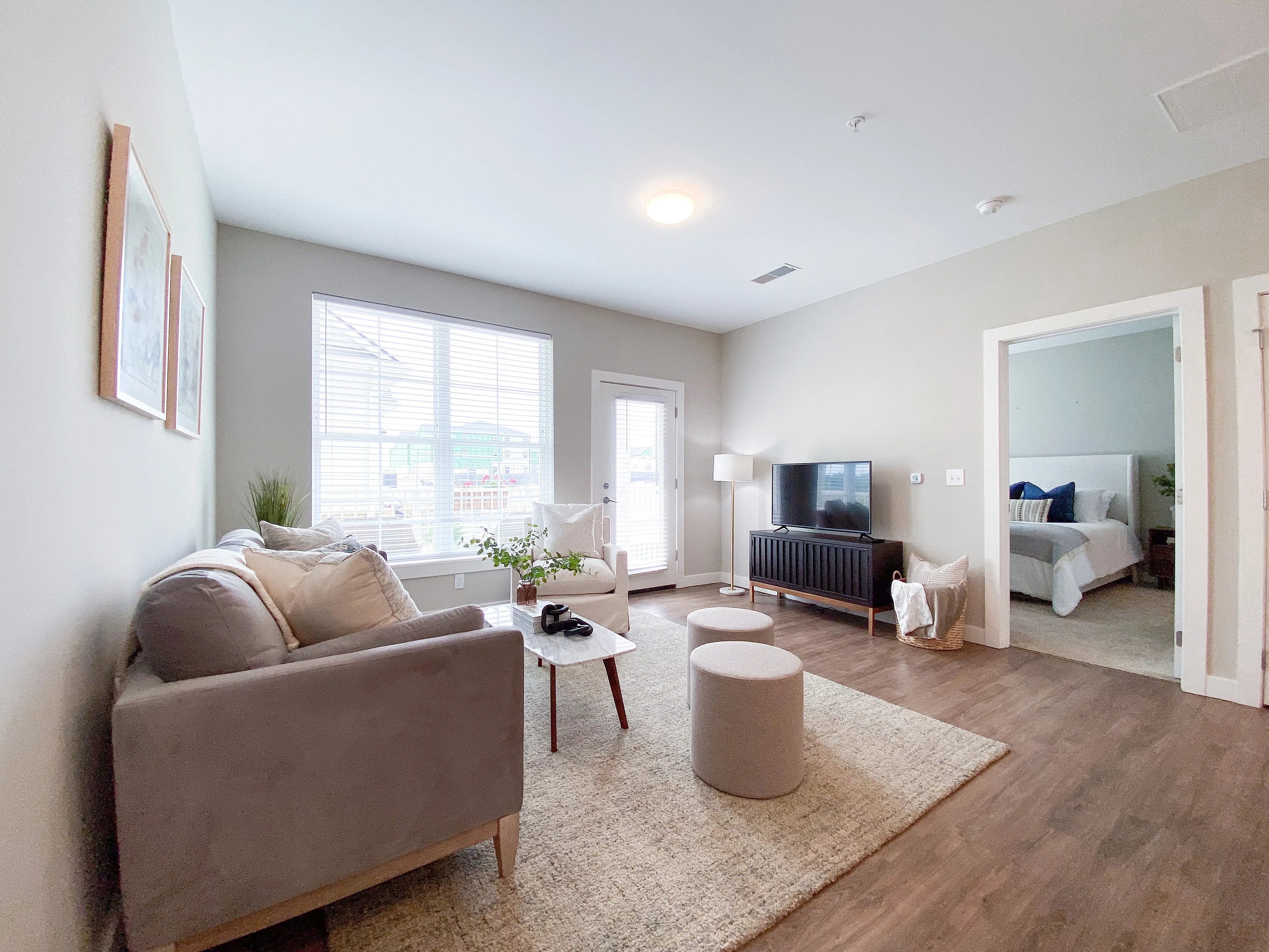 Bright and inviting living room with plush sofa, stylish decor, and adjoining bedroom in a modern apartment.
