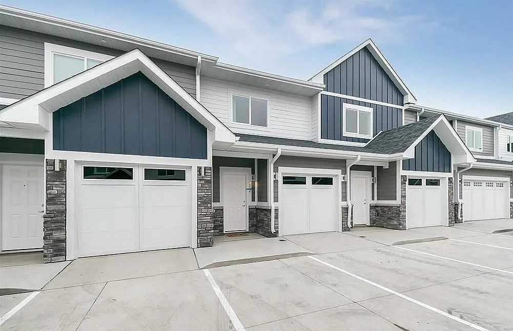 Charming townhouse exterior with modern design, featuring elegant blue and white paneling and spacious garage.