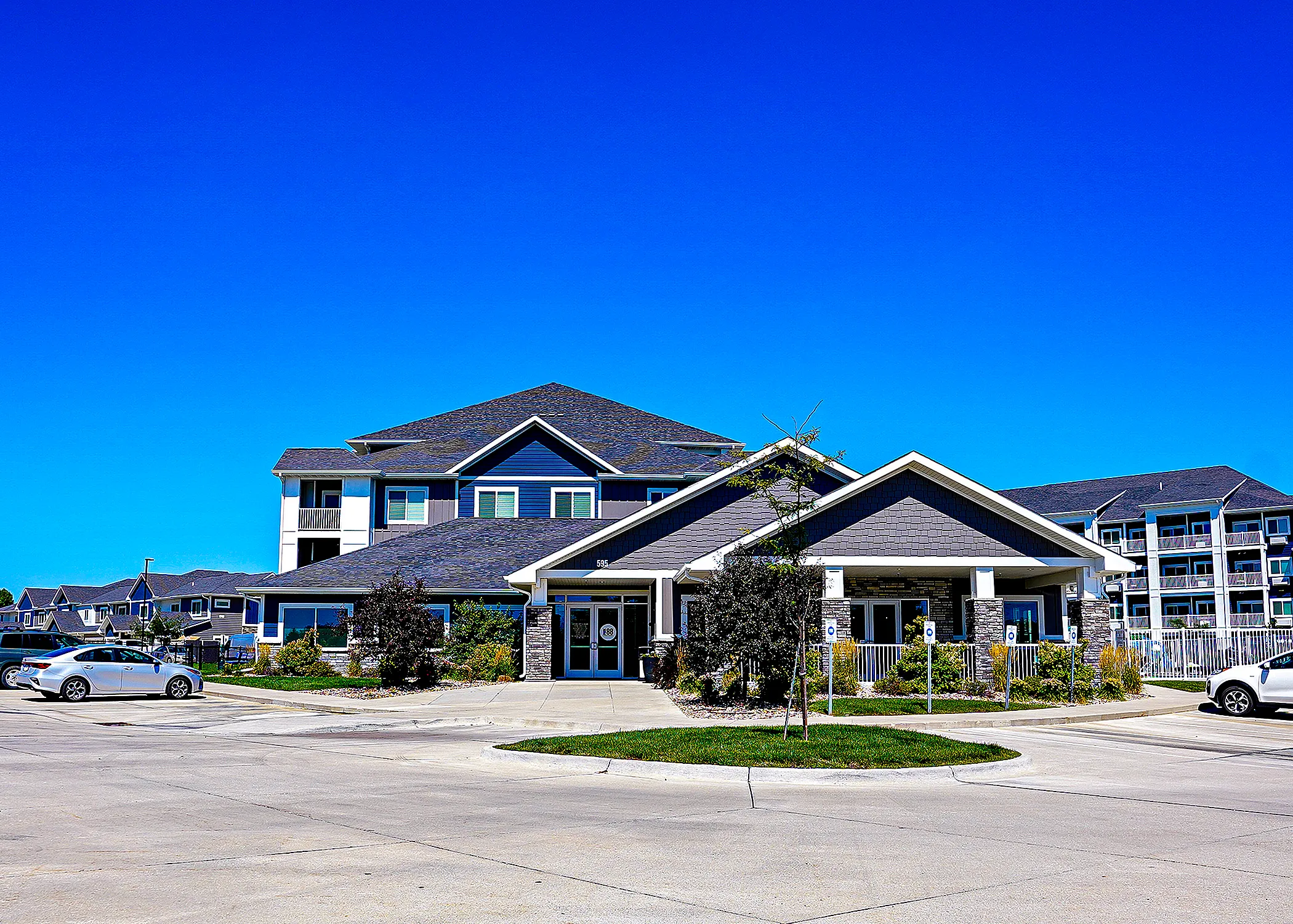 Modern apartment complex featuring multi-story buildings with stylish architecture, surrounded by lush landscaping and ample parking.