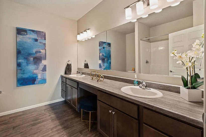 Elegant bathroom featuring a large mirror, chic lighting, and a modern vanity with decorative accents.