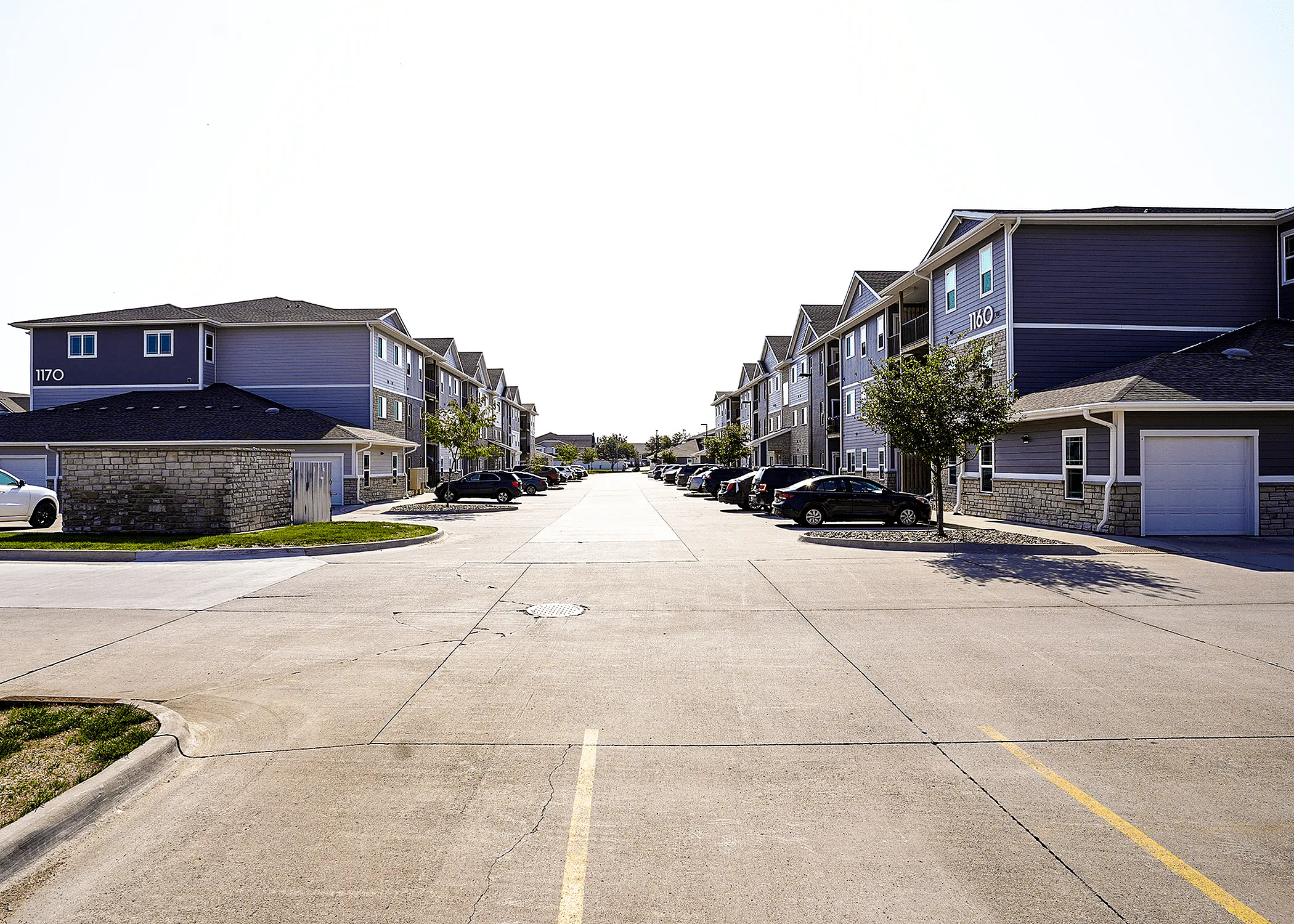 Bright and inviting apartment complex with modern architecture, ample parking, and tree-lined streets.