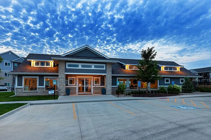Charming residential building with stone facade and warm evening lighting, nestled under a stunning blue sky.