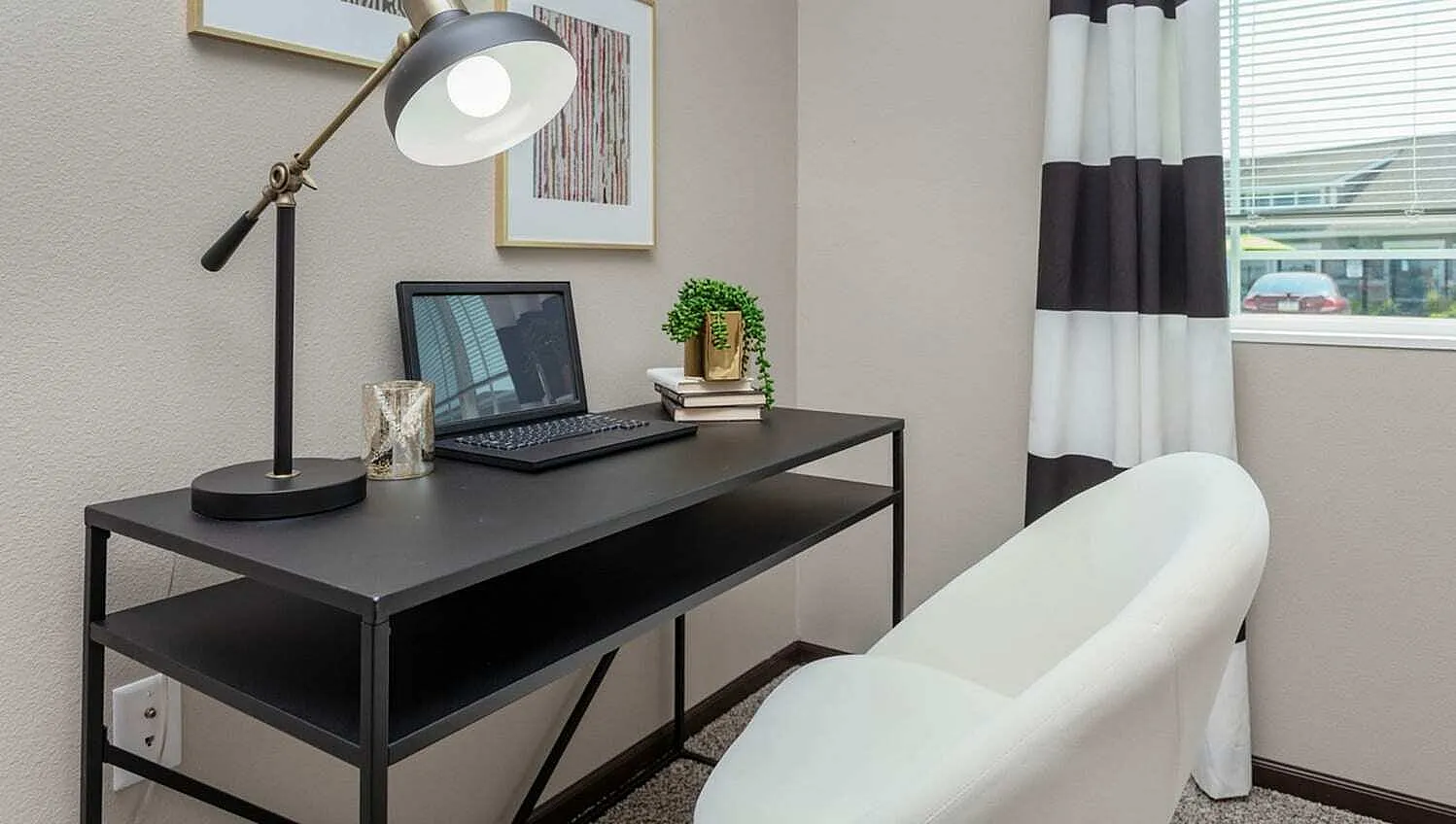 Chic home office corner with a sleek black desk, modern lamp, and cozy white chair, perfect for productivity and inspiration.