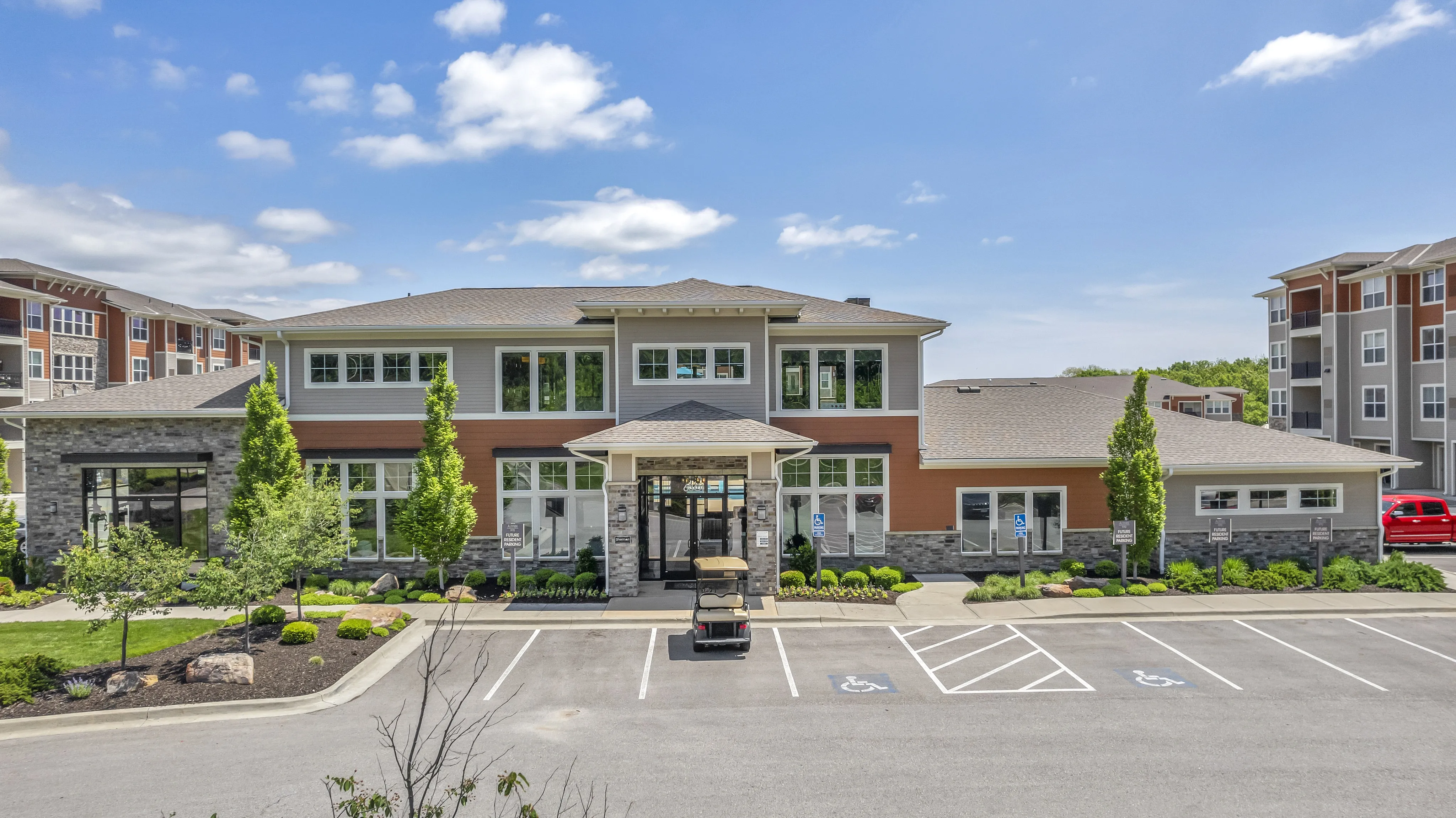 Modern apartment complex exterior with lush landscaping, expansive windows, and a sleek architectural design.