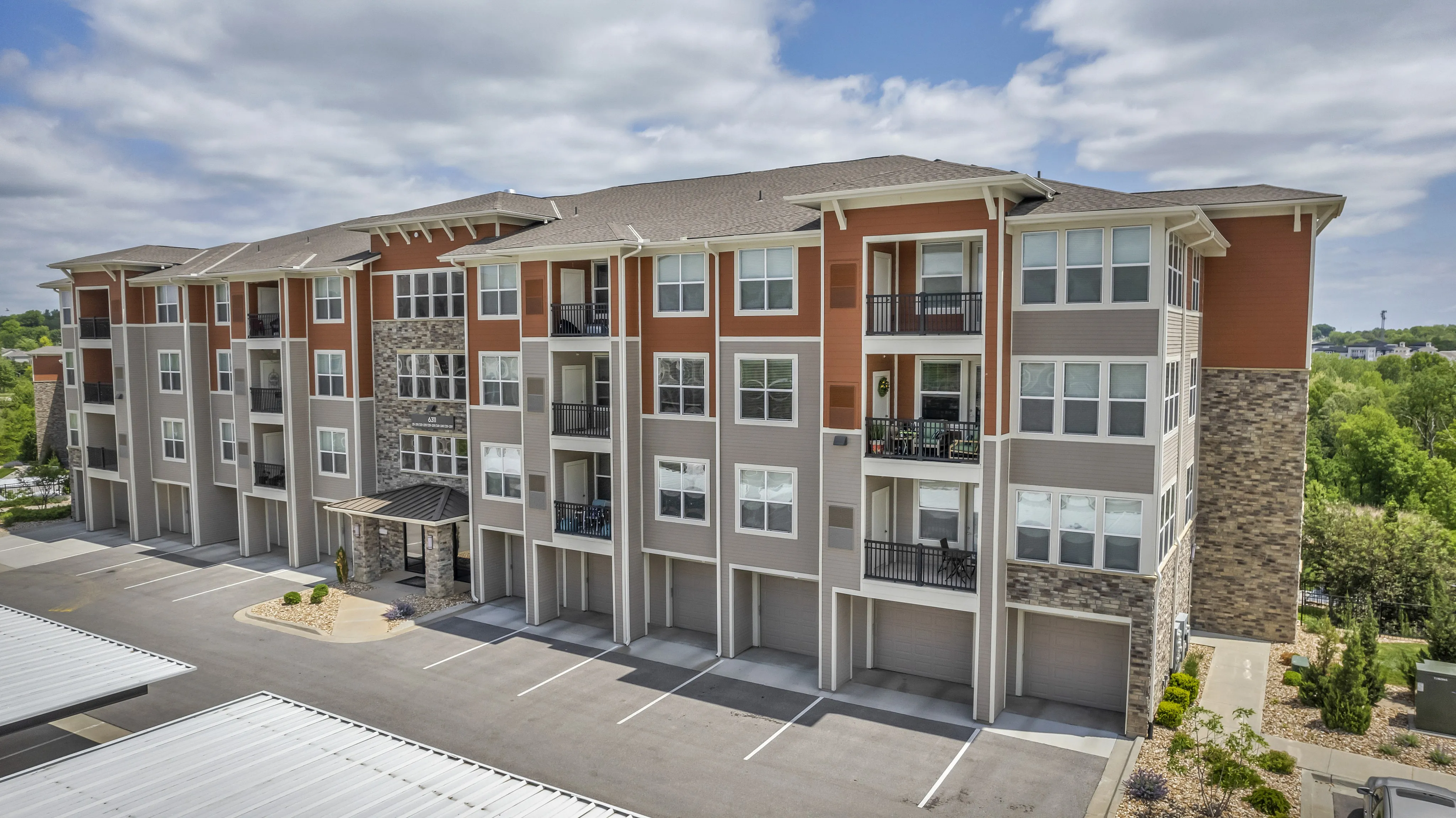 Modern apartment building with stylish design, featuring large windows, private balconies, and a beautifully landscaped entrance.