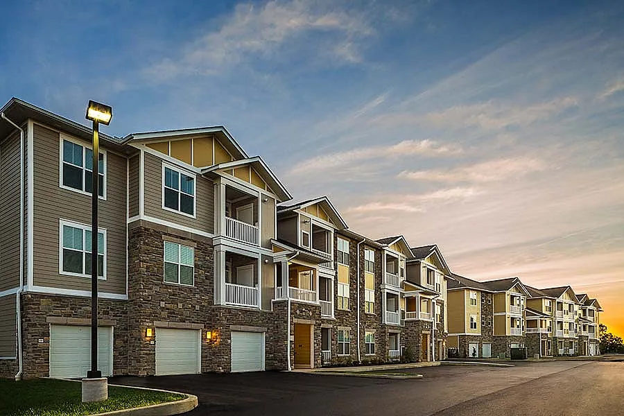 Contemporary apartment complex with elegant stonework and spacious balconies under a picturesque twilight sky.