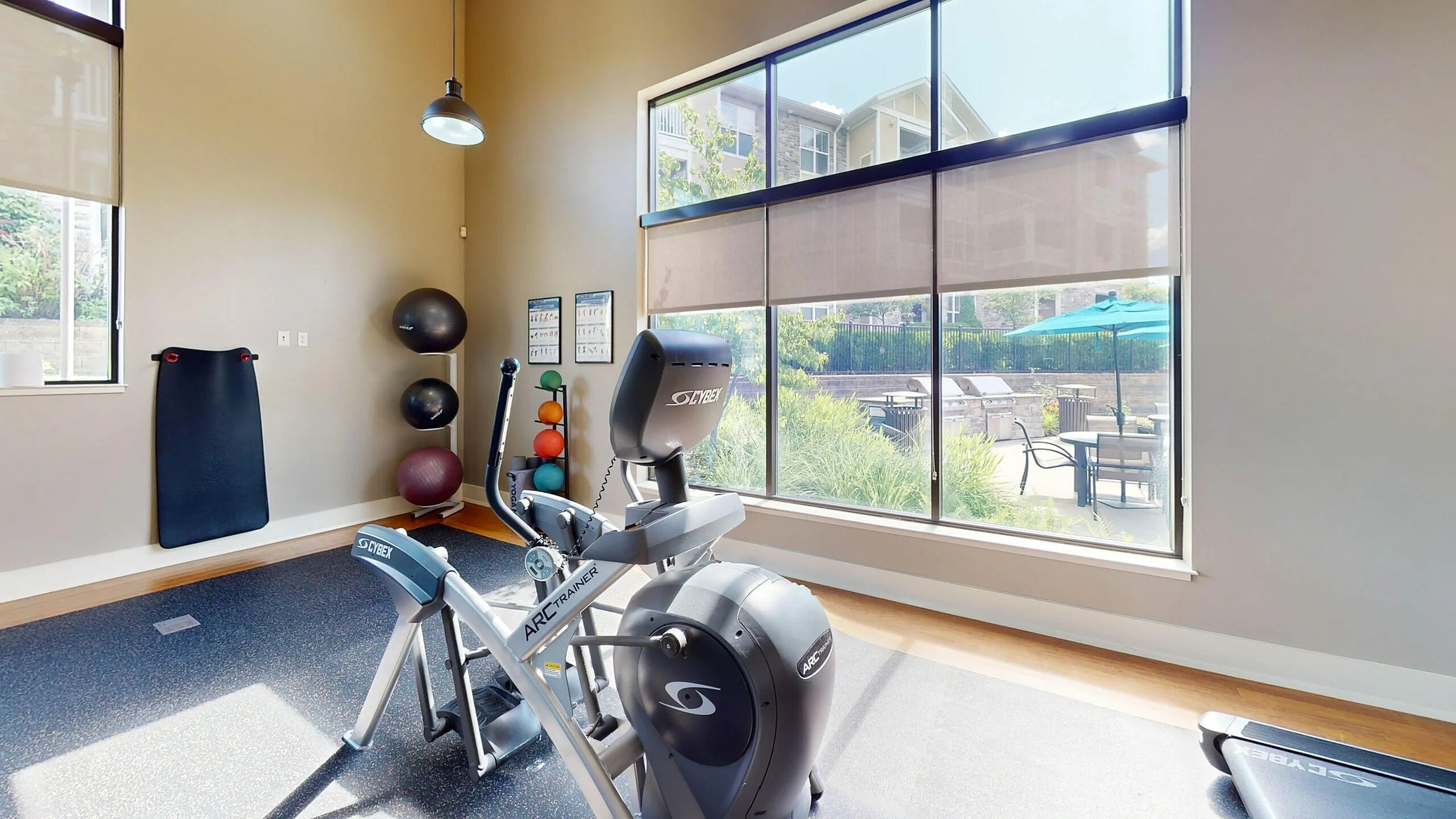 Bright and modern fitness room with state-of-the-art exercise equipment and large windows offering a serene garden view.