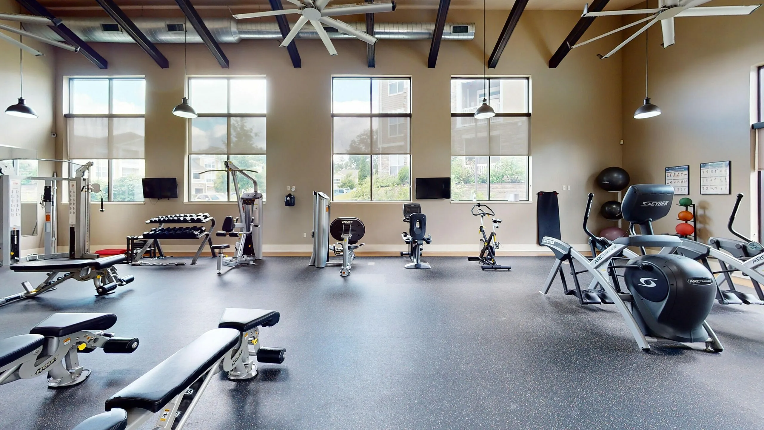 Modern fitness center with large windows, featuring top-notch gym equipment, exercise bikes, and weight benches for an energizing workout experience.