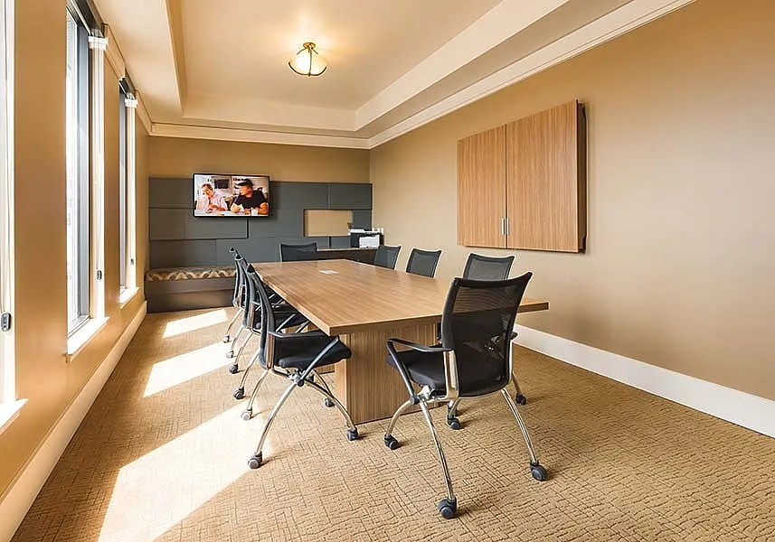 Modern and inviting conference room with natural lighting, stylish wooden table, and sleek chairs, perfect for productive meetings.