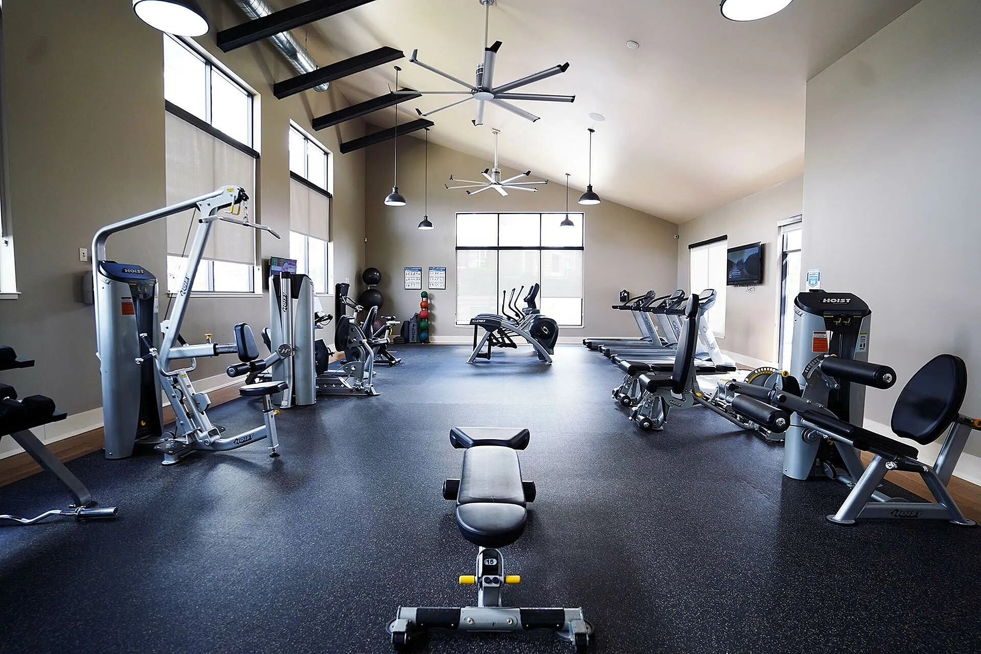 Modern fitness center with state-of-the-art gym equipment, high ceilings, and large windows offering abundant natural light.