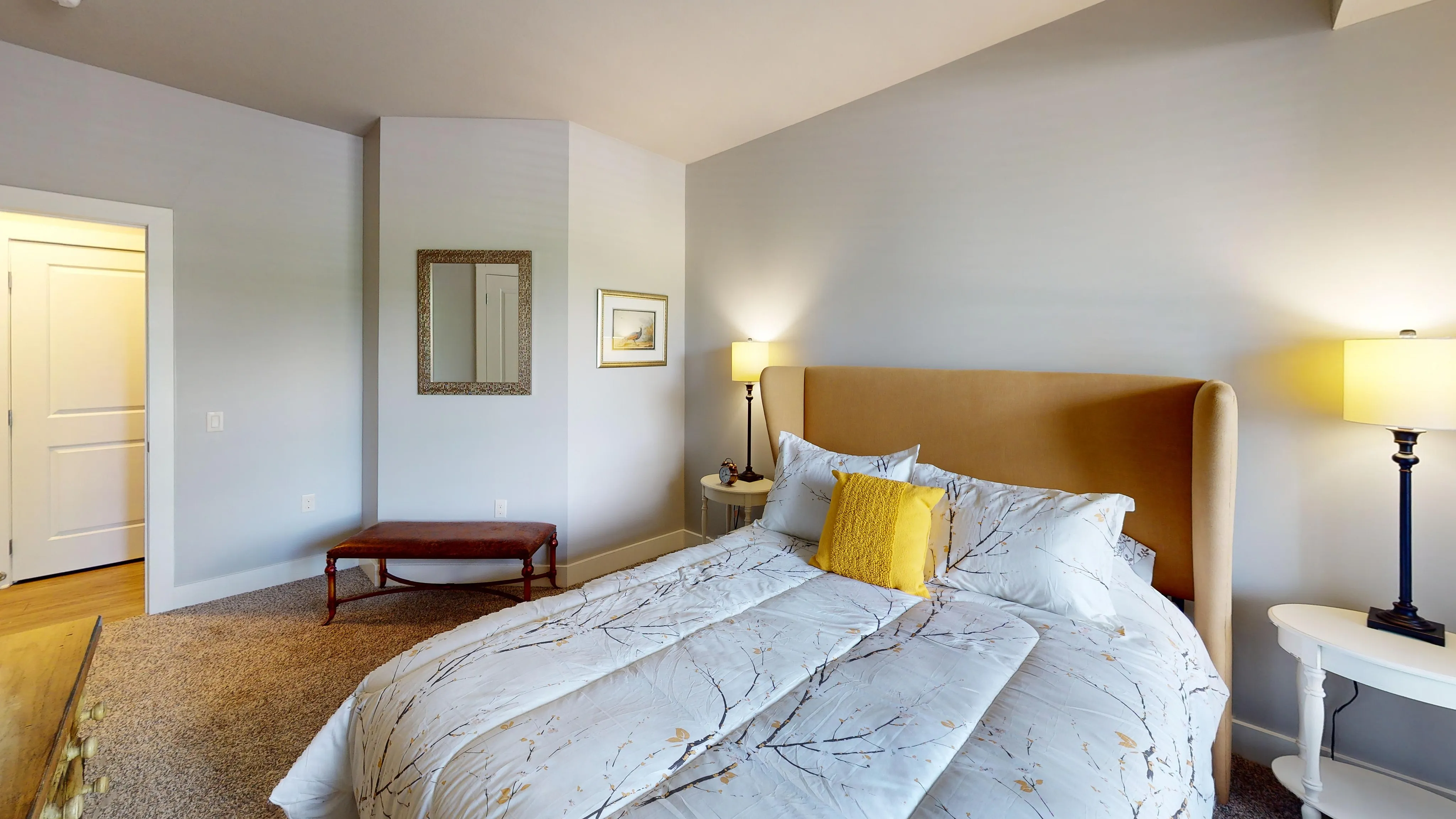 Inviting bedroom with elegant decor, featuring a plush bed adorned with floral bedding, warm lighting, and tasteful artwork, perfect for relaxation.