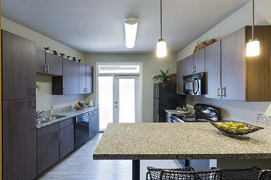 Modern kitchen featuring sleek wooden cabinets, granite countertops, and ambient lighting with a cozy atmosphere.