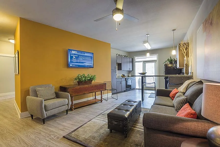 Modern open-concept living area with stylish kitchen, cozy seating, and warm accent wall.