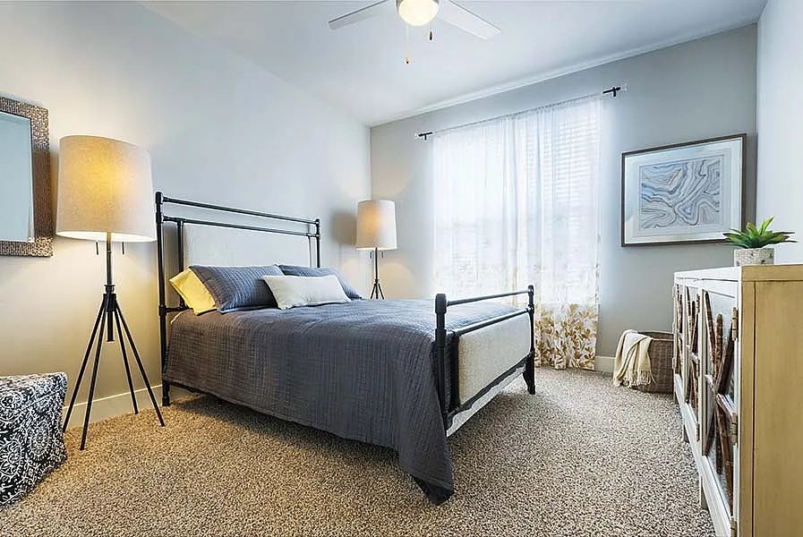 Bright and cozy bedroom featuring elegant decor, plush carpeting, and stylish lighting, creating a peaceful retreat.