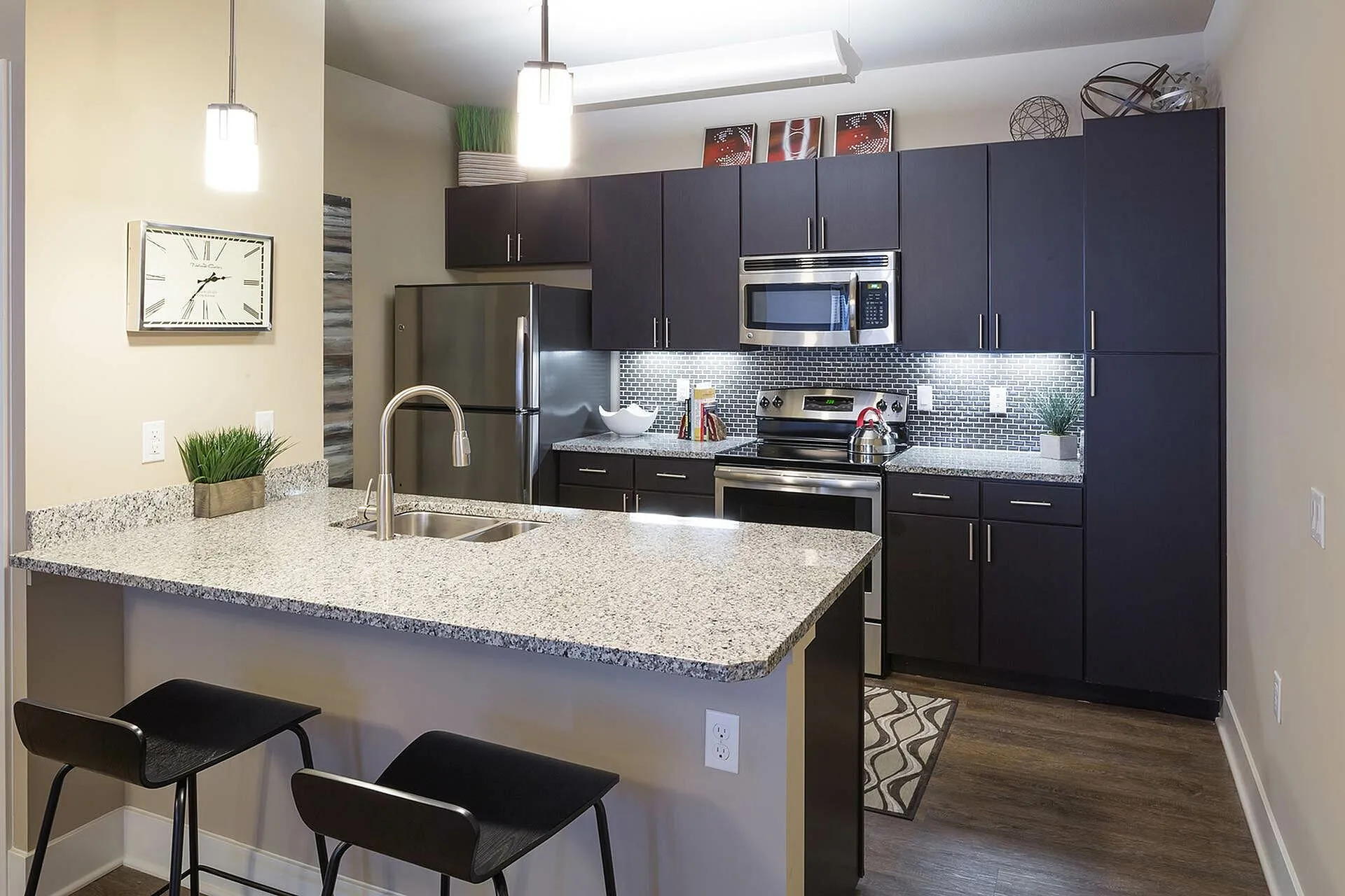 Modern kitchen with sleek dark cabinets, stainless steel appliances, and a chic granite island with bar seating.