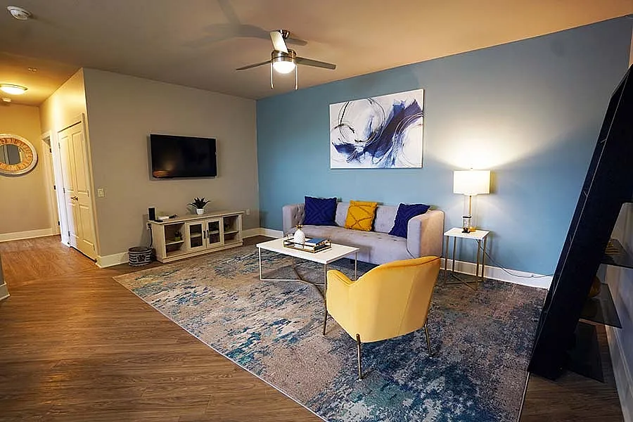 Inviting living room with modern decor featuring a cozy sofa, vibrant yellow chair, and elegant abstract art on a blue accent wall.