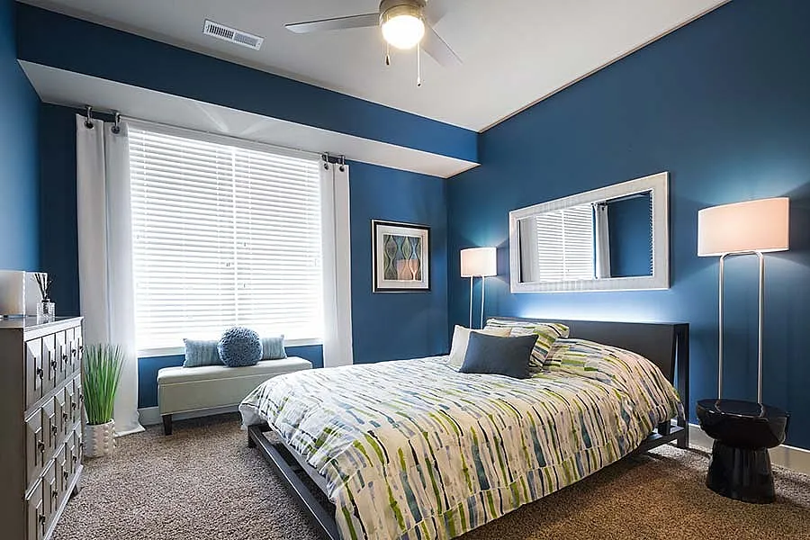 Chic bedroom with serene blue walls, stylish decor, and natural light enhancing a cozy ambiance.