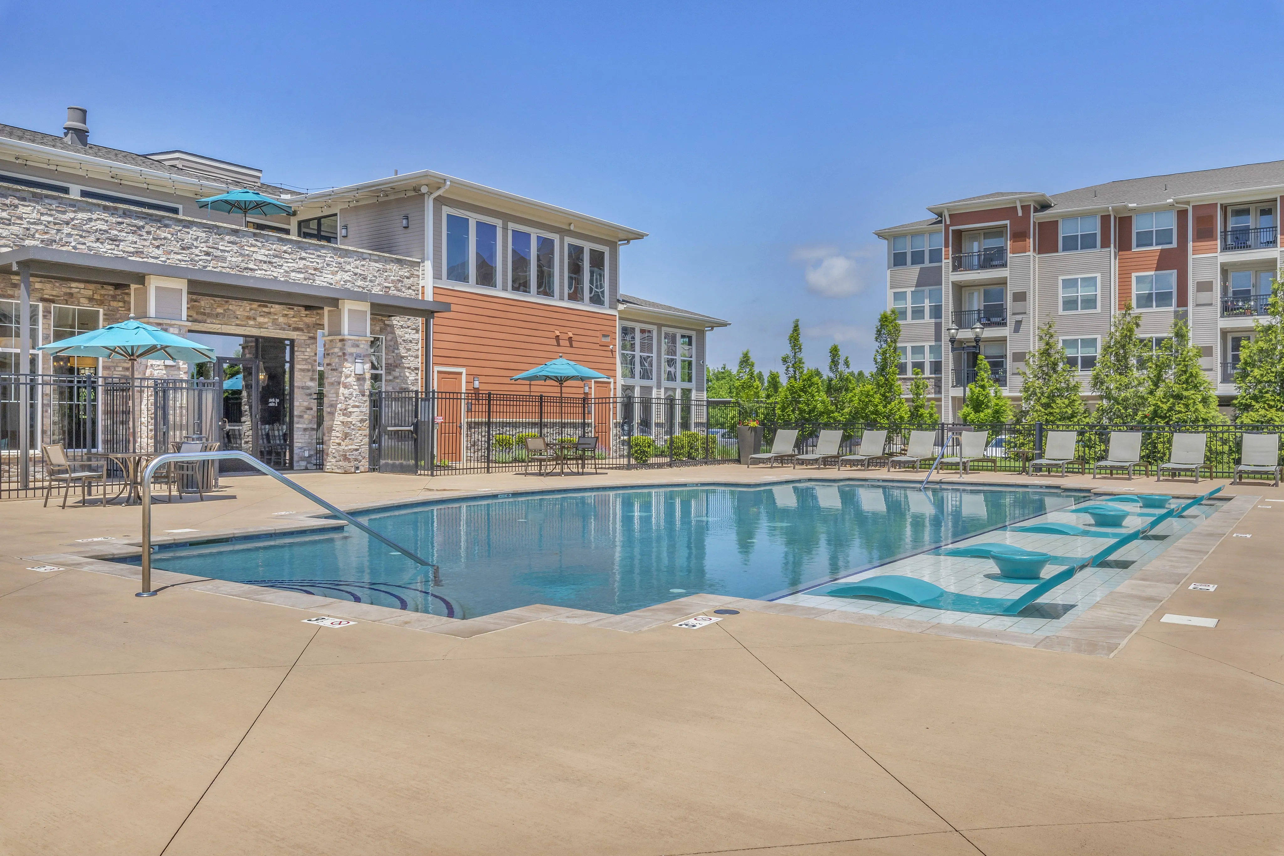 Luxurious apartment complex featuring a pristine outdoor pool with elegant poolside seating and modern architecture.