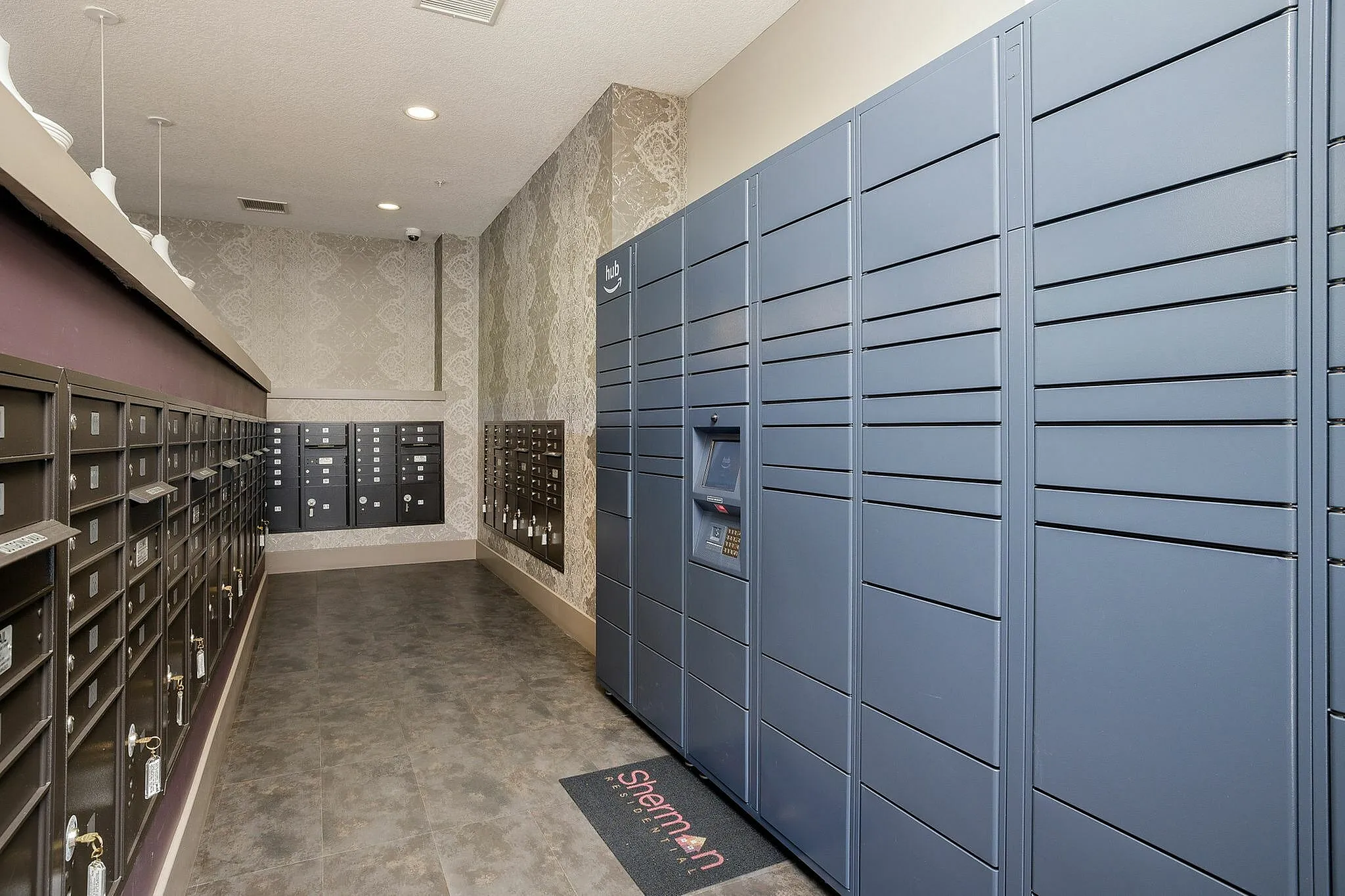 Modern apartment mailroom featuring an Amazon Hub locker and secure mailboxes, with elegant wallpaper and sleek lighting fixtures.