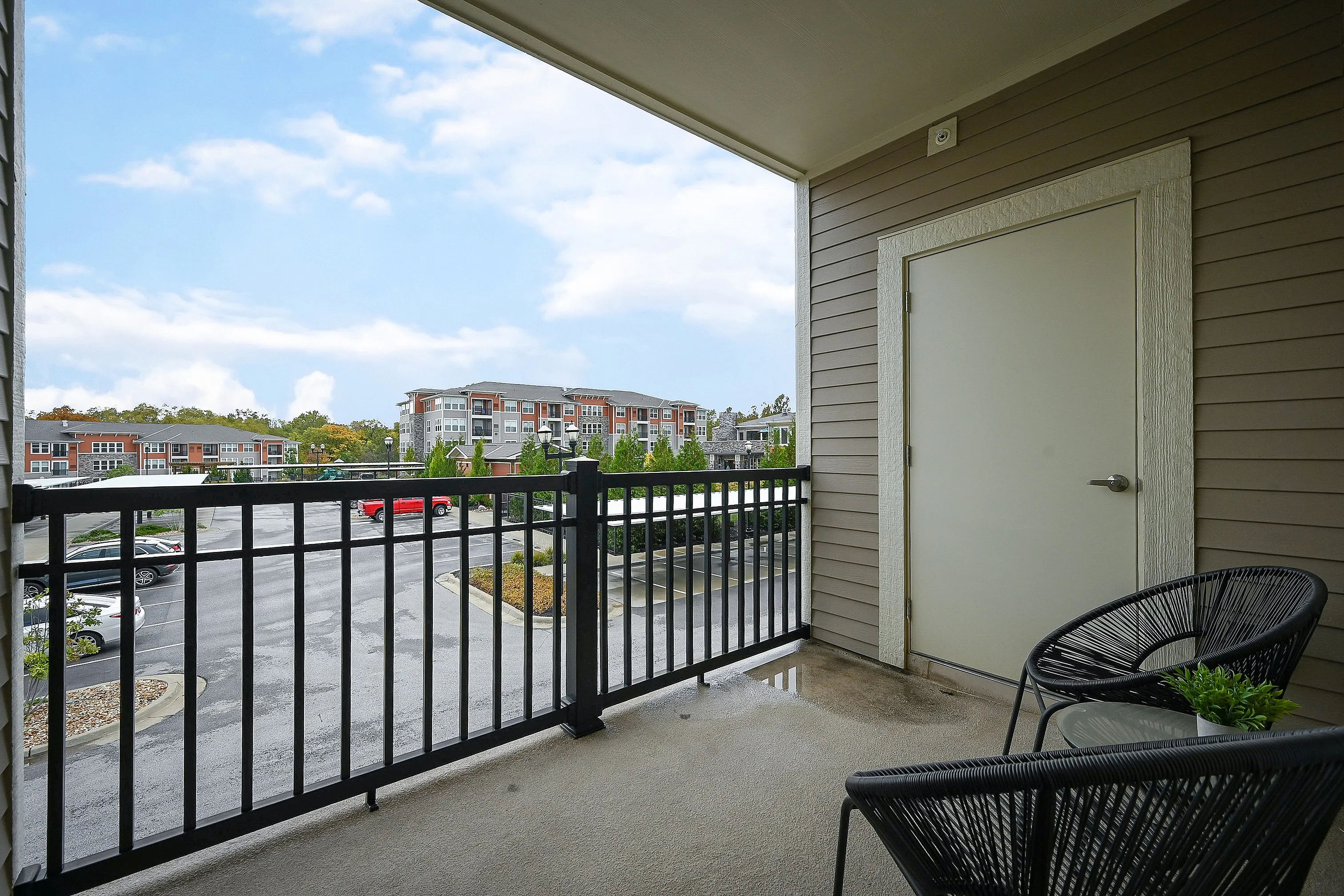 Charming balcony view overlooking modern apartment buildings, featuring stylish outdoor chairs and a serene atmosphere.