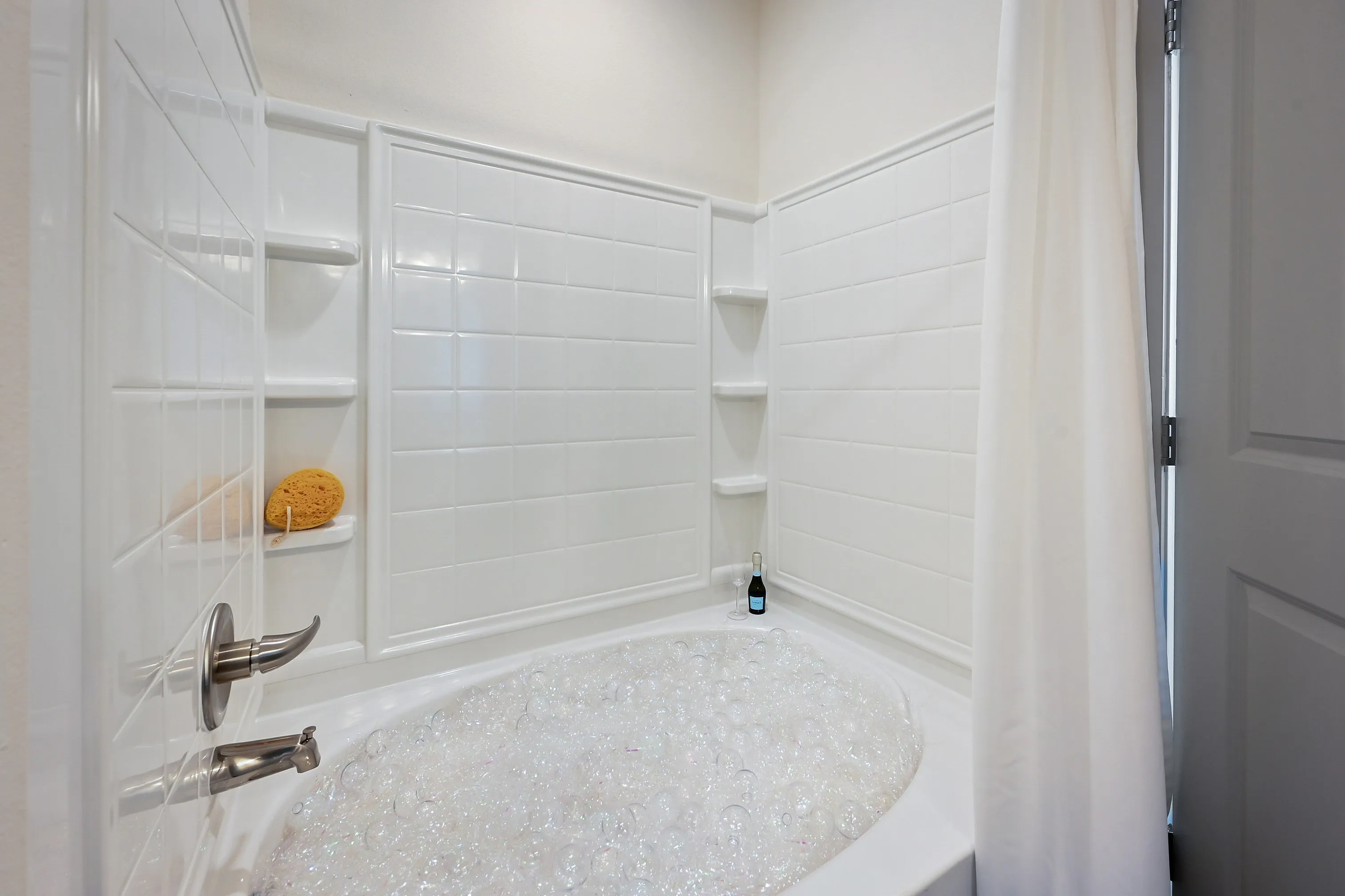 Luxurious soaking bathtub with frothy bubbles, complemented by elegant tiled walls, a refreshing spa-like ambiance.