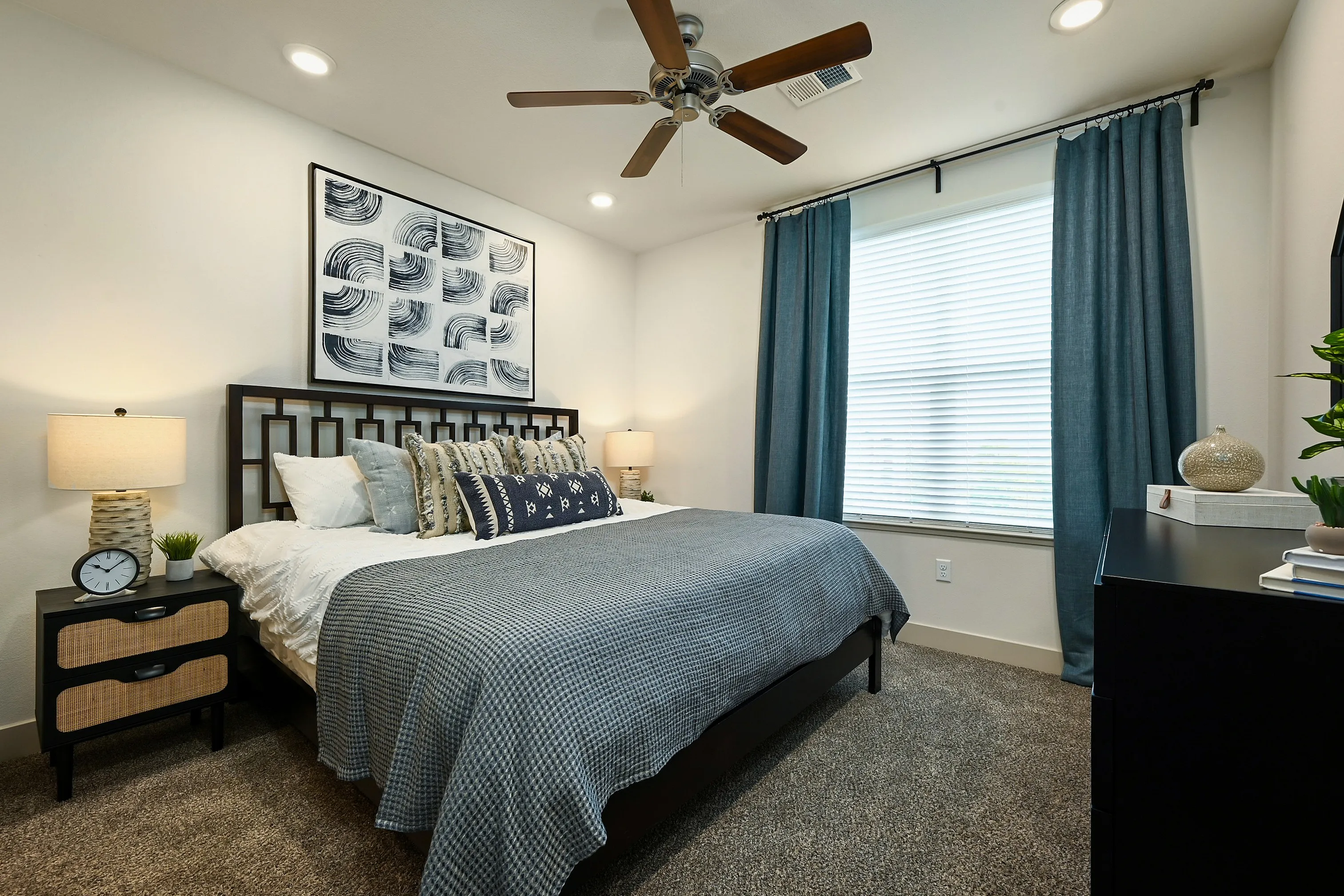 Elegant bedroom featuring a modern bed frame, stylish art piece, and soothing blue curtains for a serene ambiance.