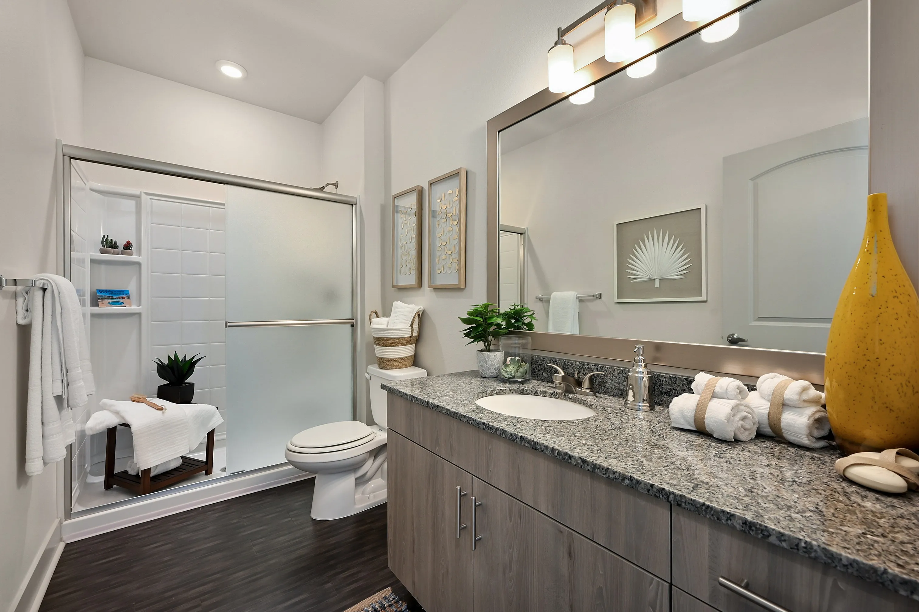 Elegantly modern bathroom with granite countertop, sleek shower enclosure, and stylish decor accents.
