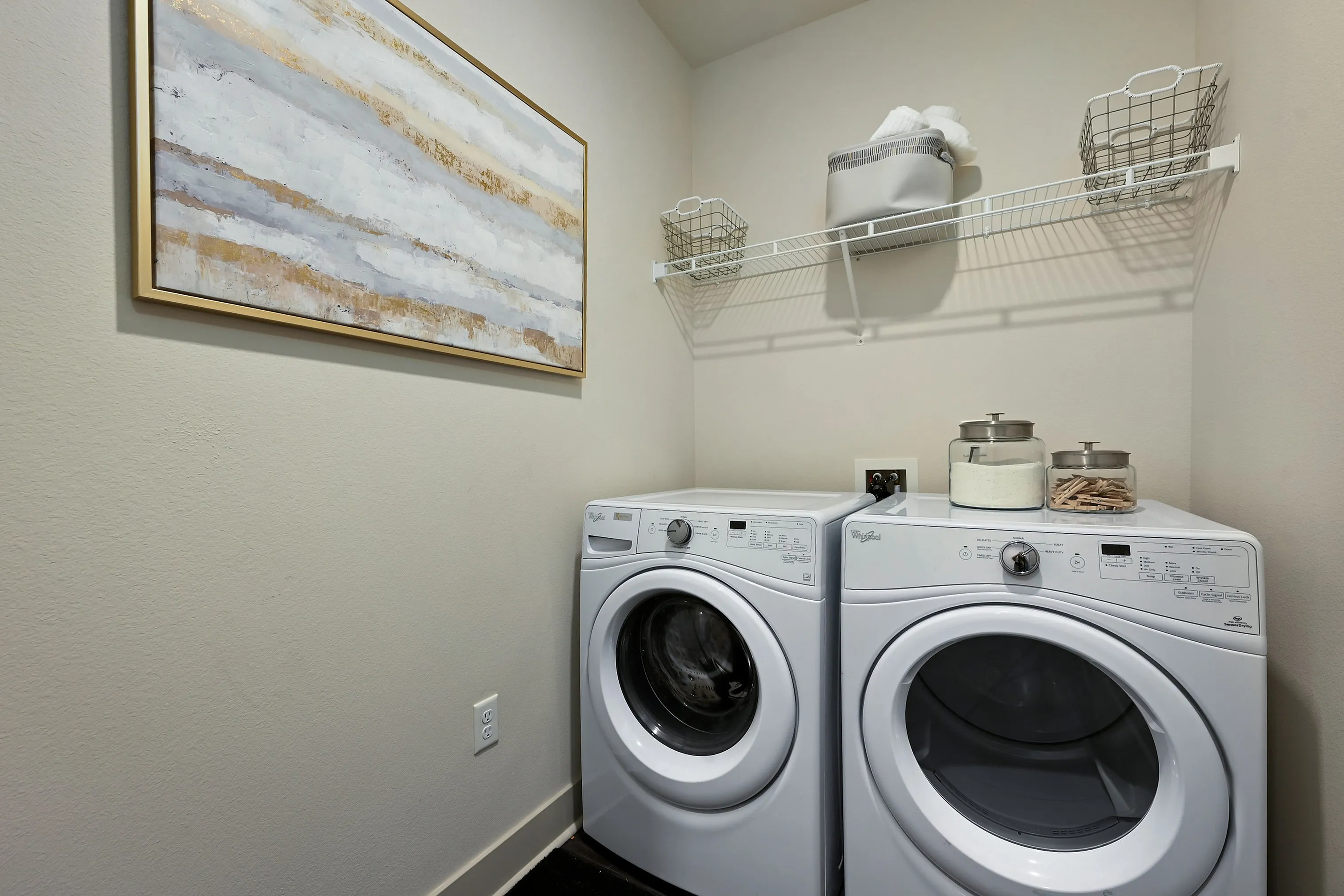 Modern laundry room featuring energy-efficient washer and dryer, stylish shelving, and contemporary wall art.