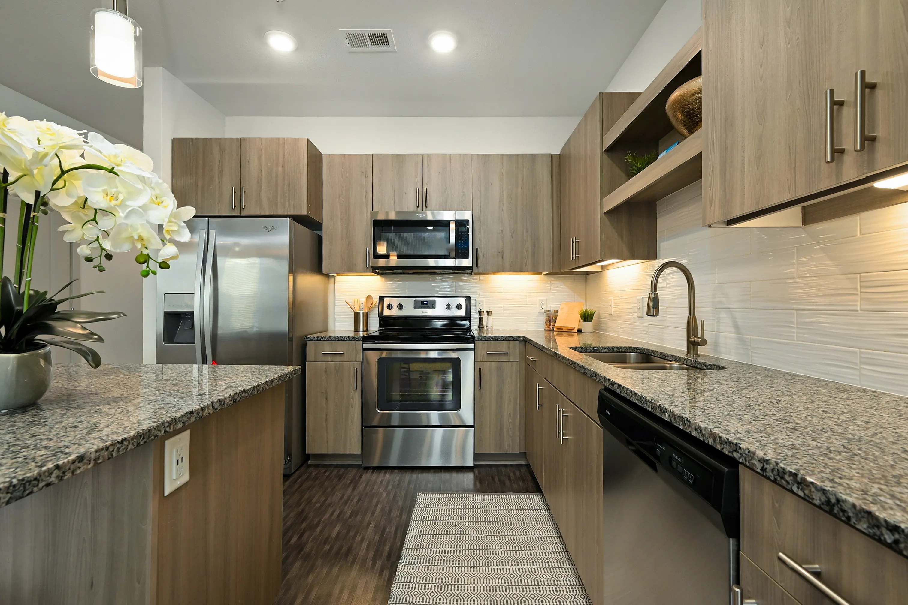 Modern kitchen with stainless steel appliances, elegant wooden cabinetry, and sleek granite countertops.