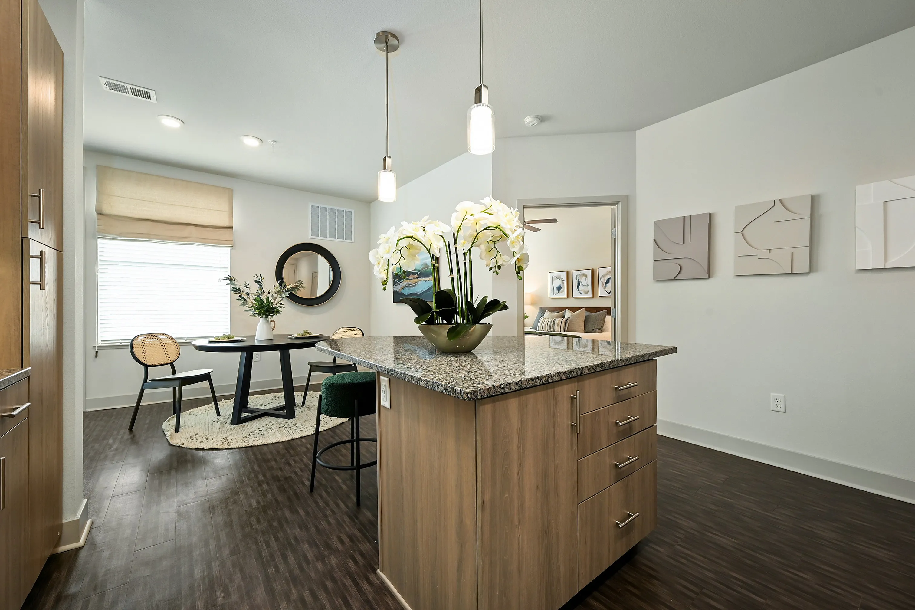 Modern kitchen with granite island, chic dining area, and elegant decor in a bright, open-concept apartment.