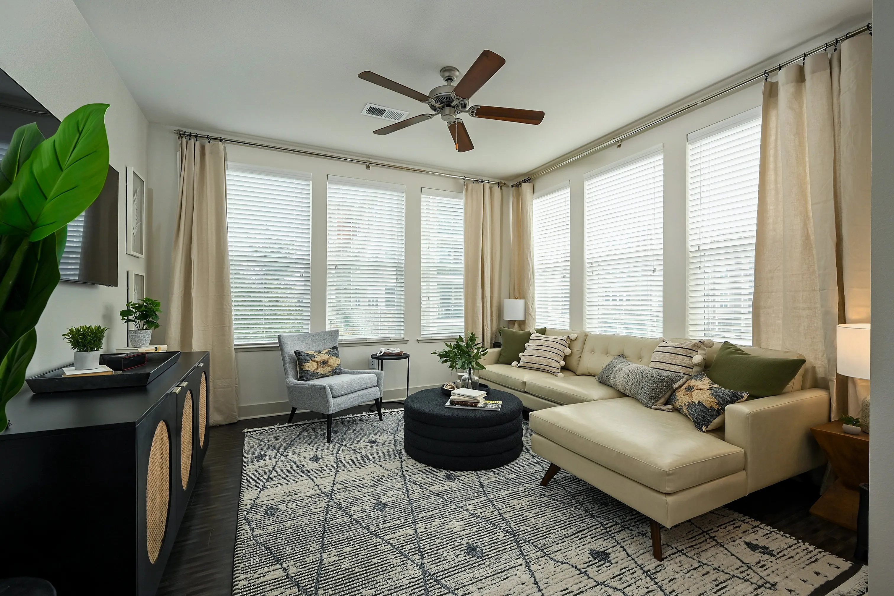 Inviting living room with modern decor, neutral tones, cozy sectional sofa, and abundant natural light from large windows.