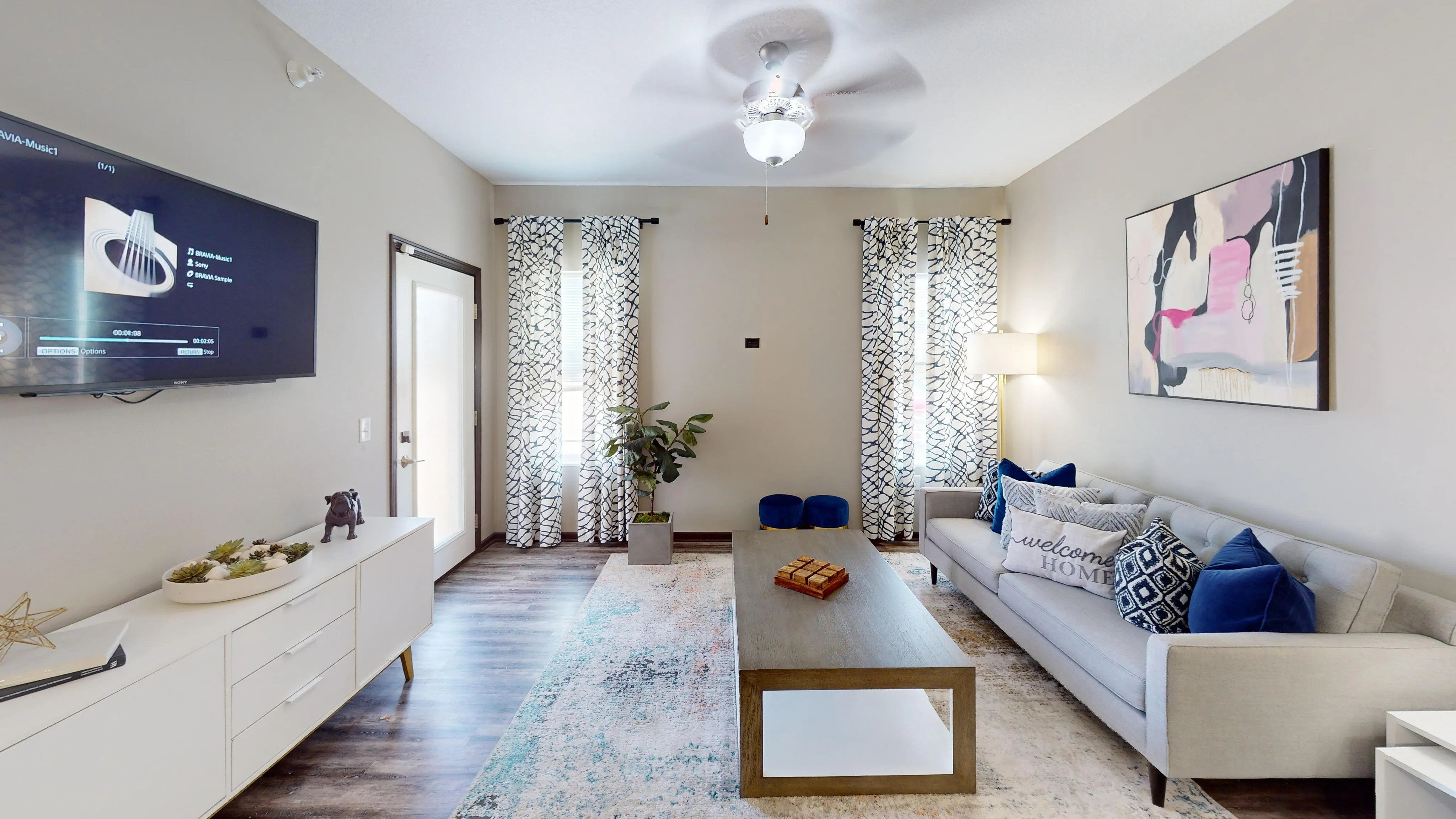 Modern living room with elegant decor, abstract artwork, and a cozy gray sofa with vibrant blue cushions.